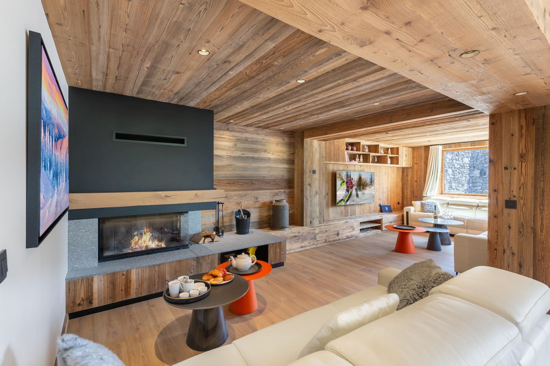 Living area with wood-burning fireplace and secondary lounge with media wall