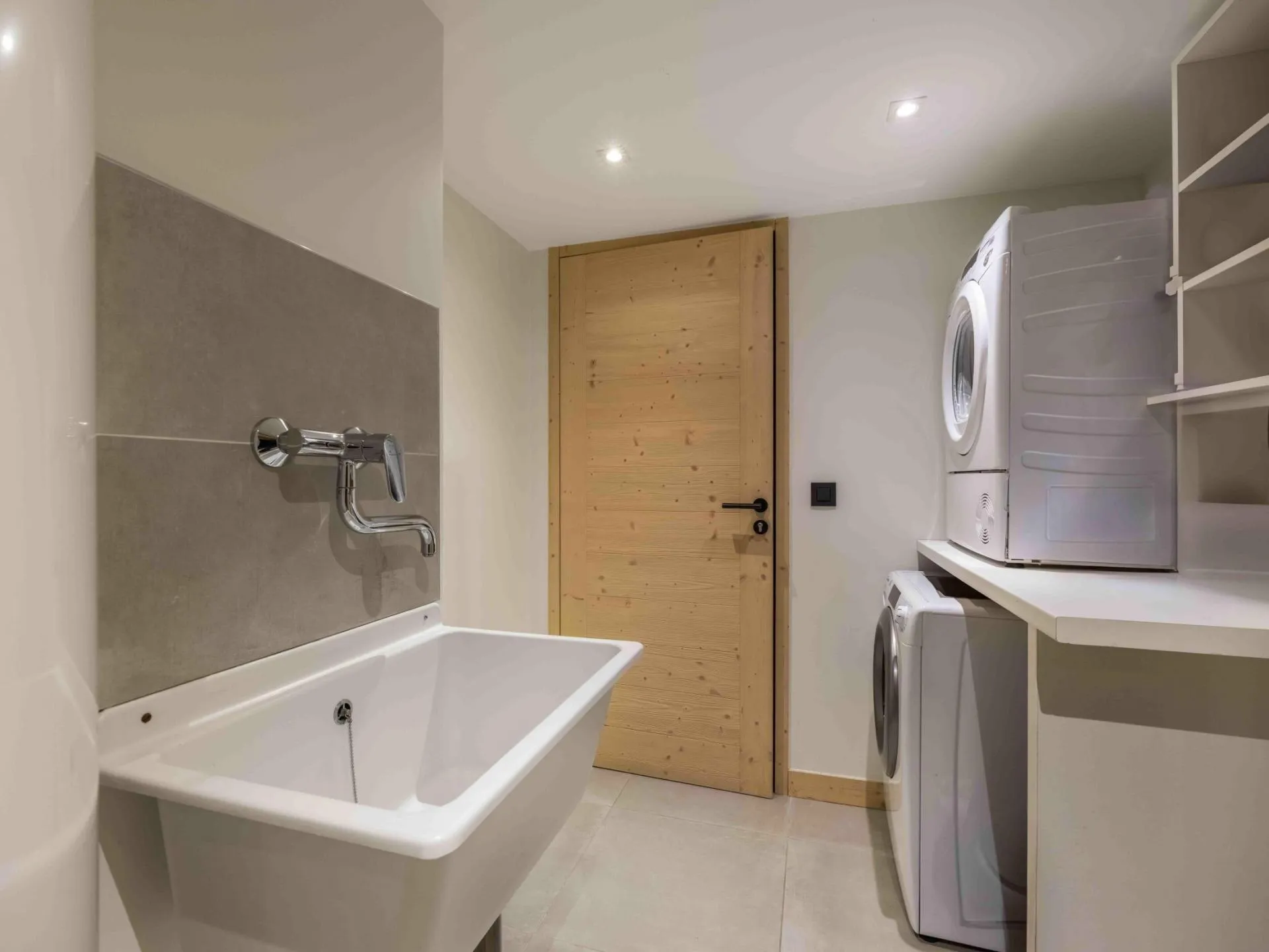 Laundry room with stacked machines and a utility sink