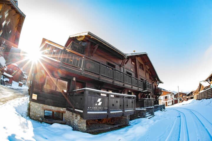 Timber chalet exterior with multiple private balconies and snowy village road access