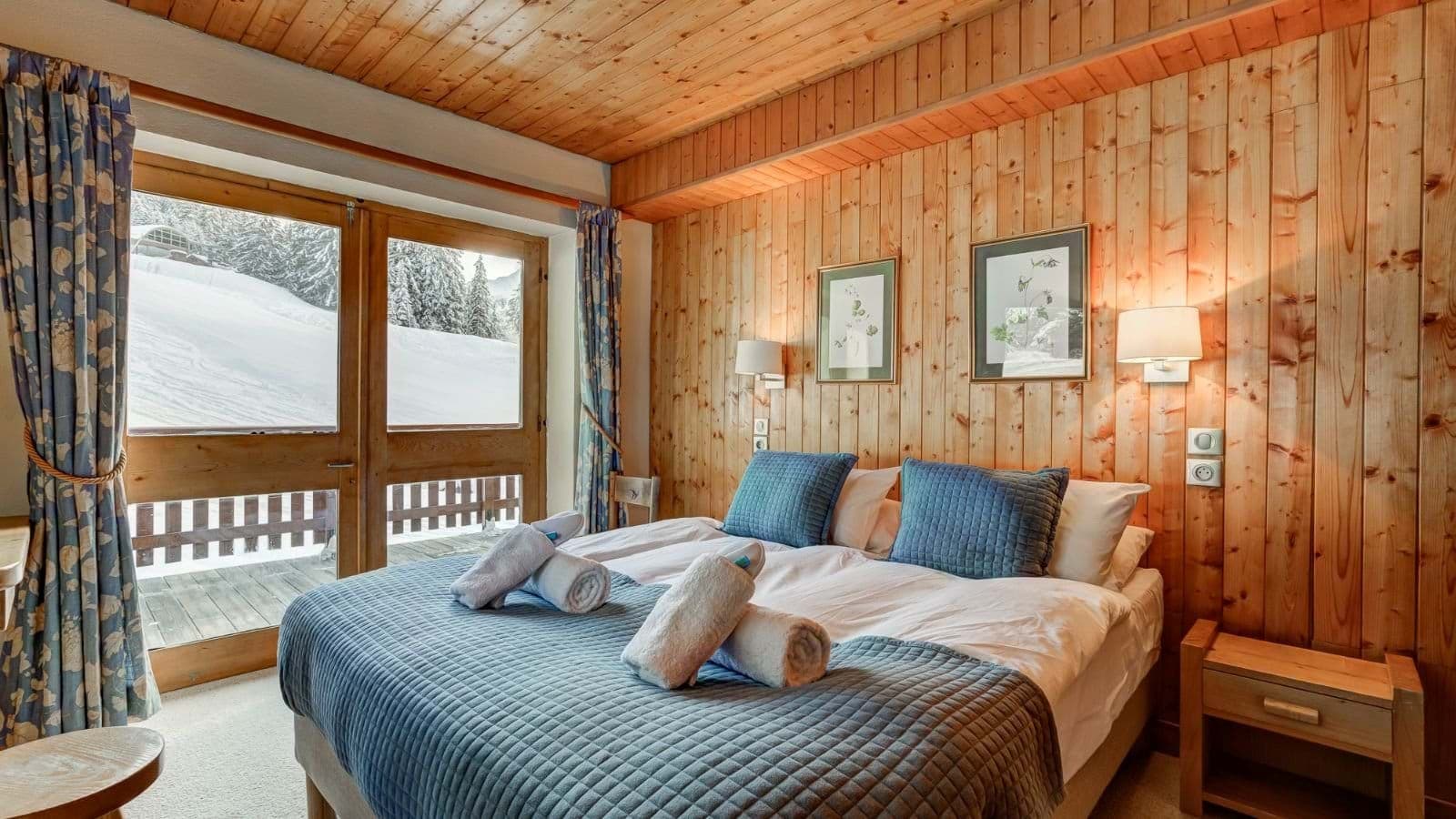 Bedroom with twin beds, wood-paneled walls, and private balcony access