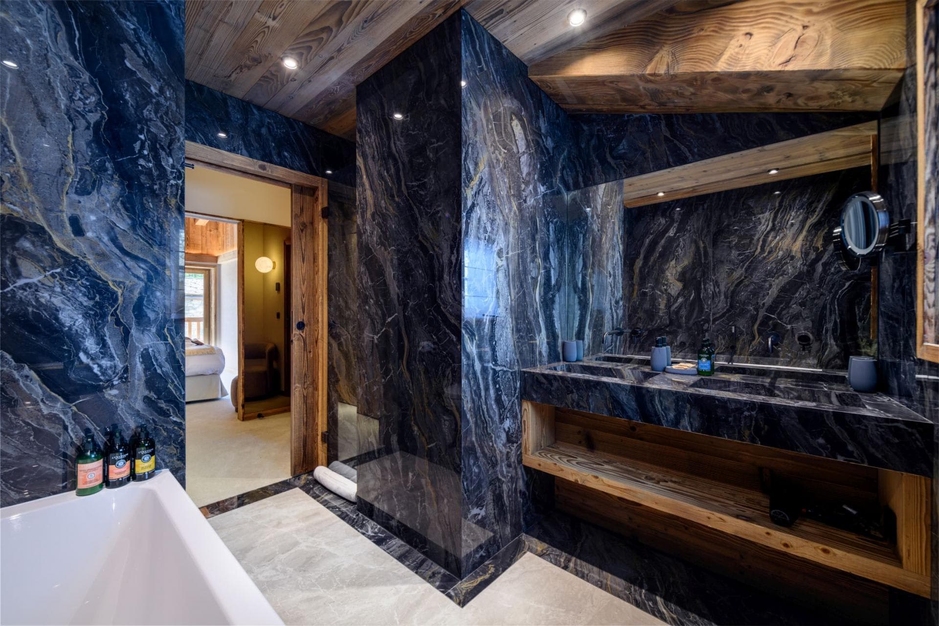 Bathroom with marble finishes, dual sinks, and deep soaking tub
