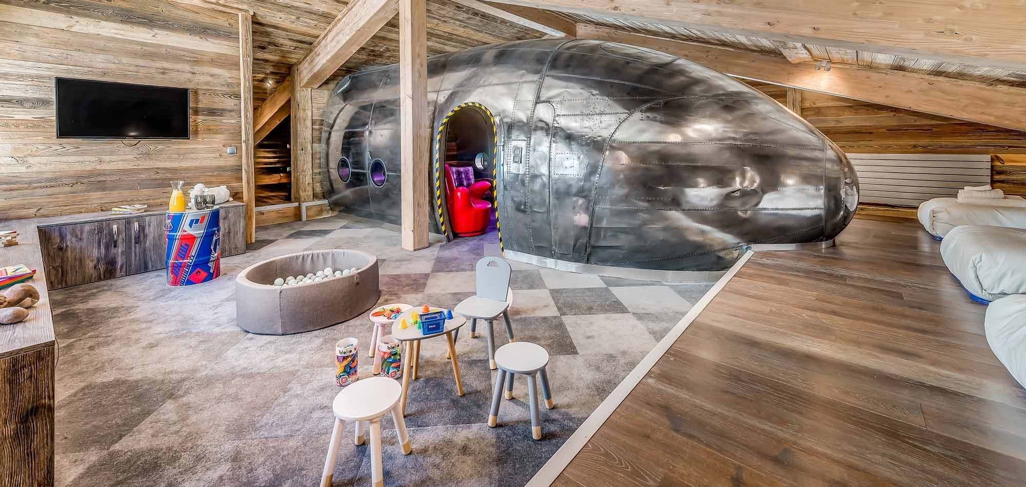 Kids' playroom with fuselage-themed play area, ball pit, and floor seating