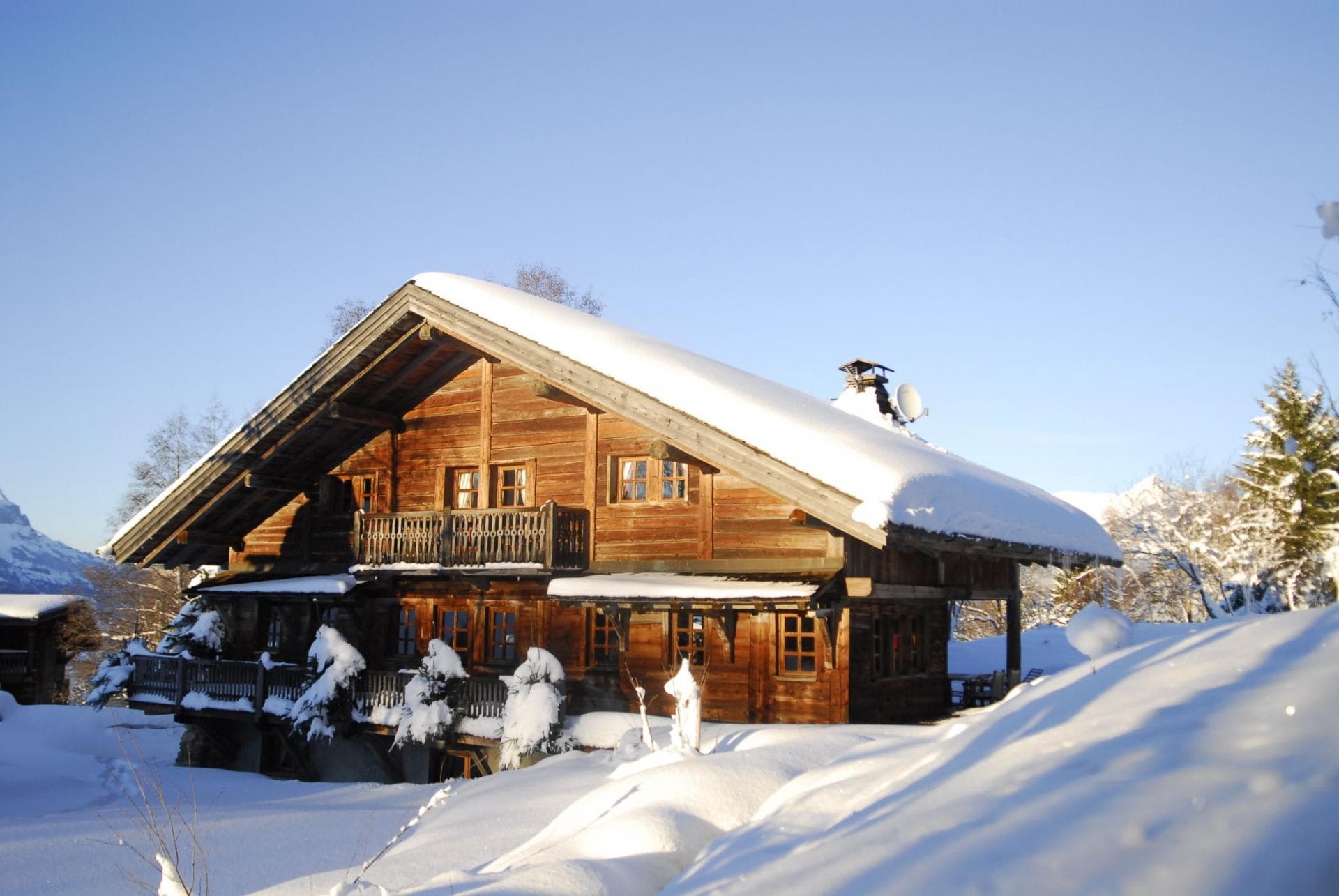 Three-story timber chalet featuring private balconies in a snowy mountain landscape