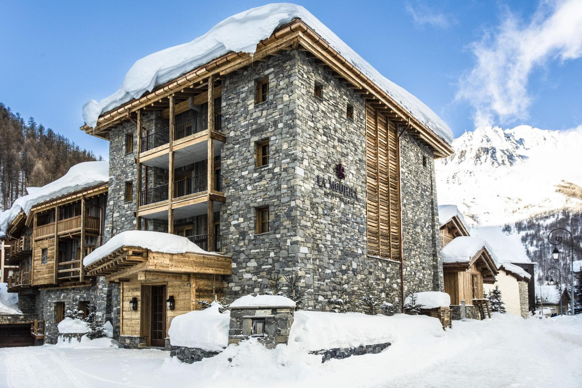 Stone chalet exterior with private balconies and snow-covered mountain backdrop