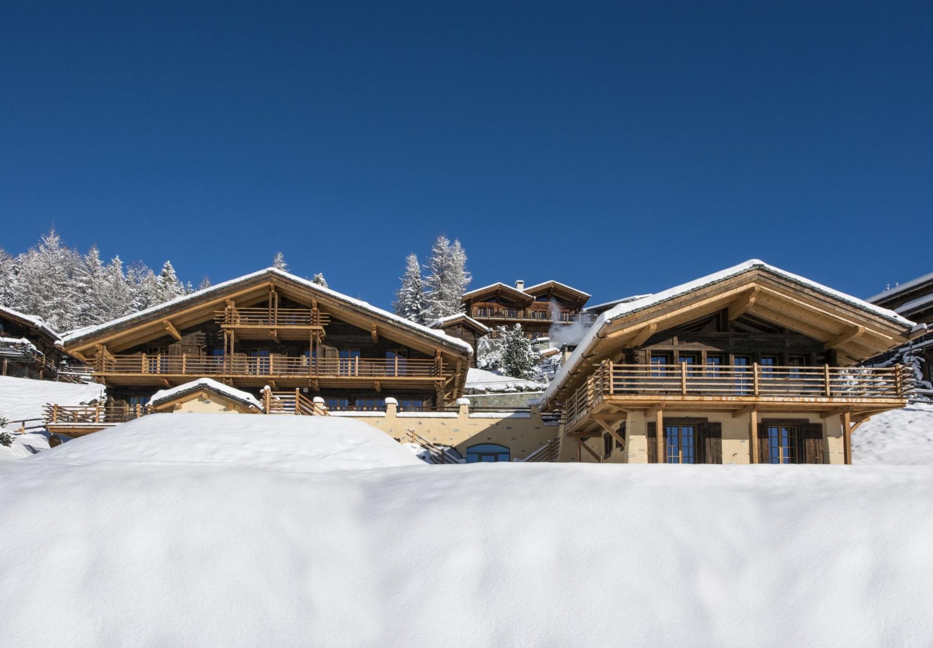 Paired timber chalets with wrap-around balconies and mountain views