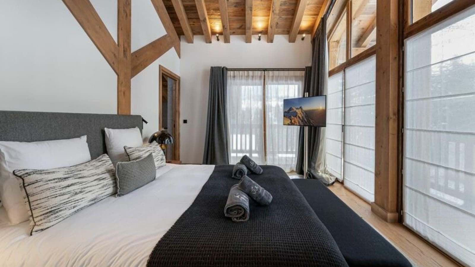 Primary bedroom with timber-beamed ceiling and floor-to-ceiling windows