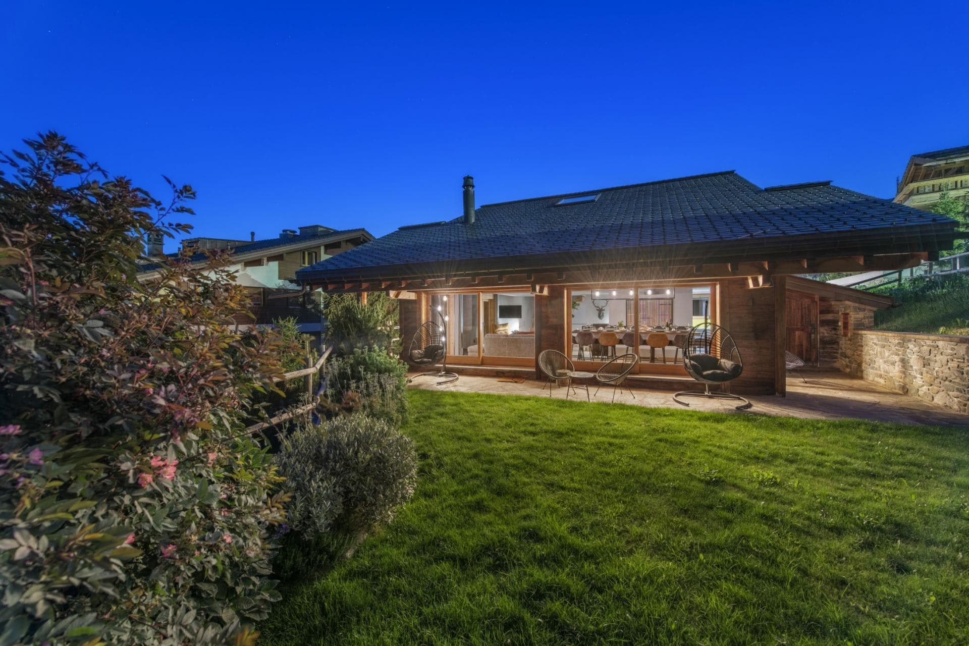 Private lawn and patio with hanging egg chairs and outdoor seating