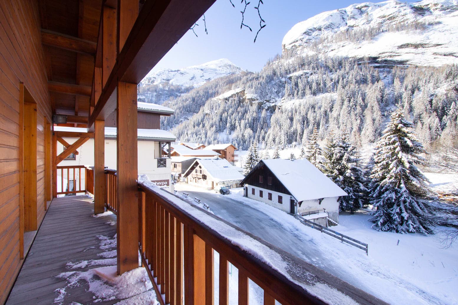 Covered wooden balcony with views of village and snow-covered mountains