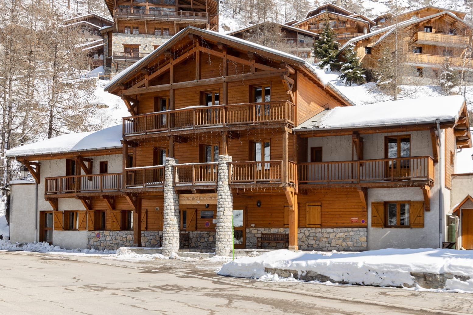 Ski-in chalet exterior with multi-level timber balconies and street-level access