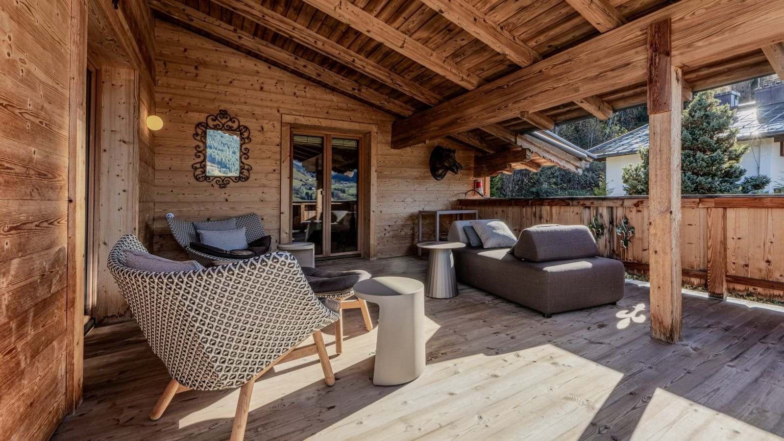 Covered wooden balcony with lounge seating and mountain views