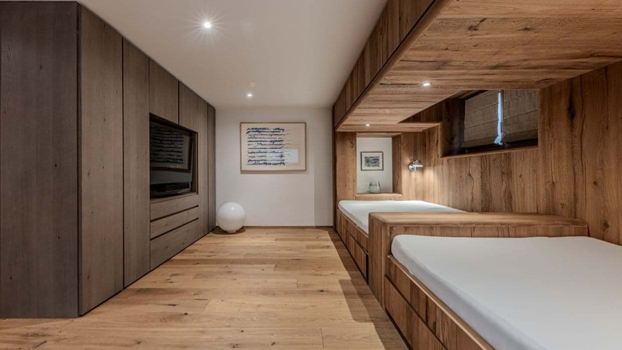 Bunk room with custom built-in beds and wall-mounted television