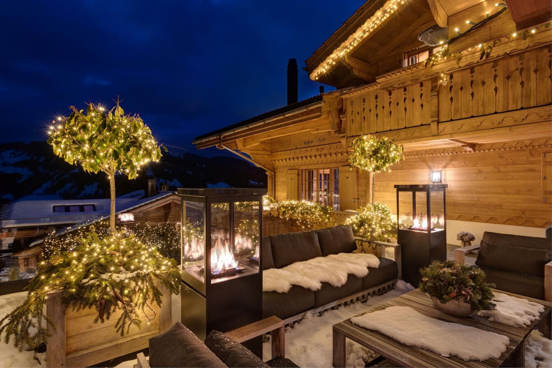 Chalet terrace with outdoor sofas and twin glass-enclosed gas fire pits