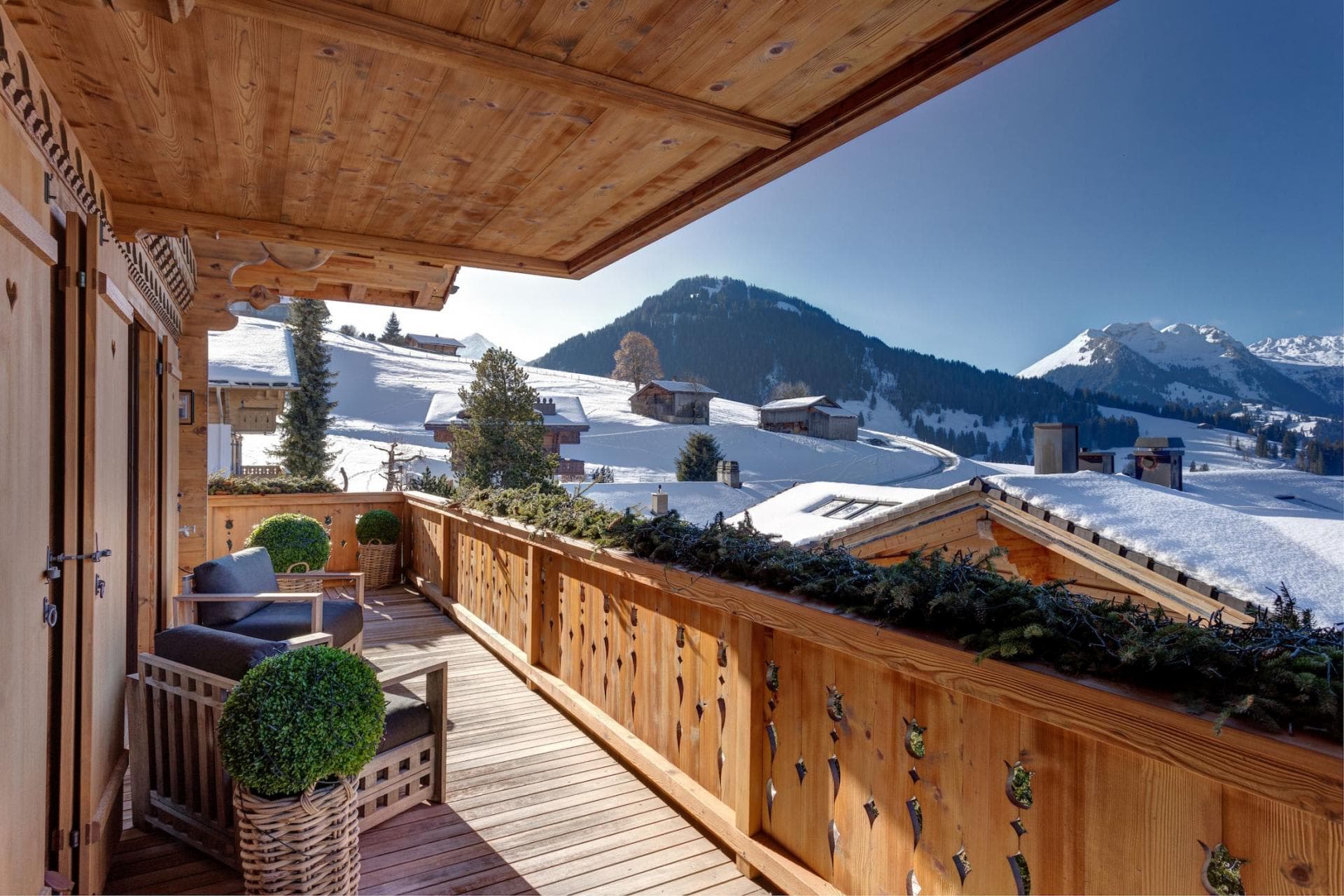Covered wooden balcony with lounge seating and panoramic mountain views