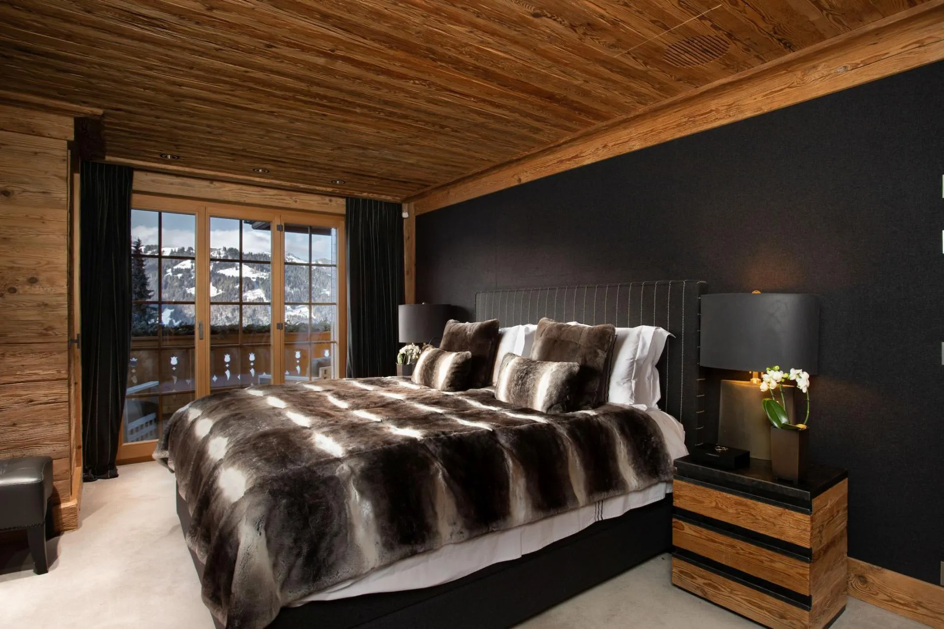 Primary bedroom with king bed, reclaimed wood ceiling, and private balcony