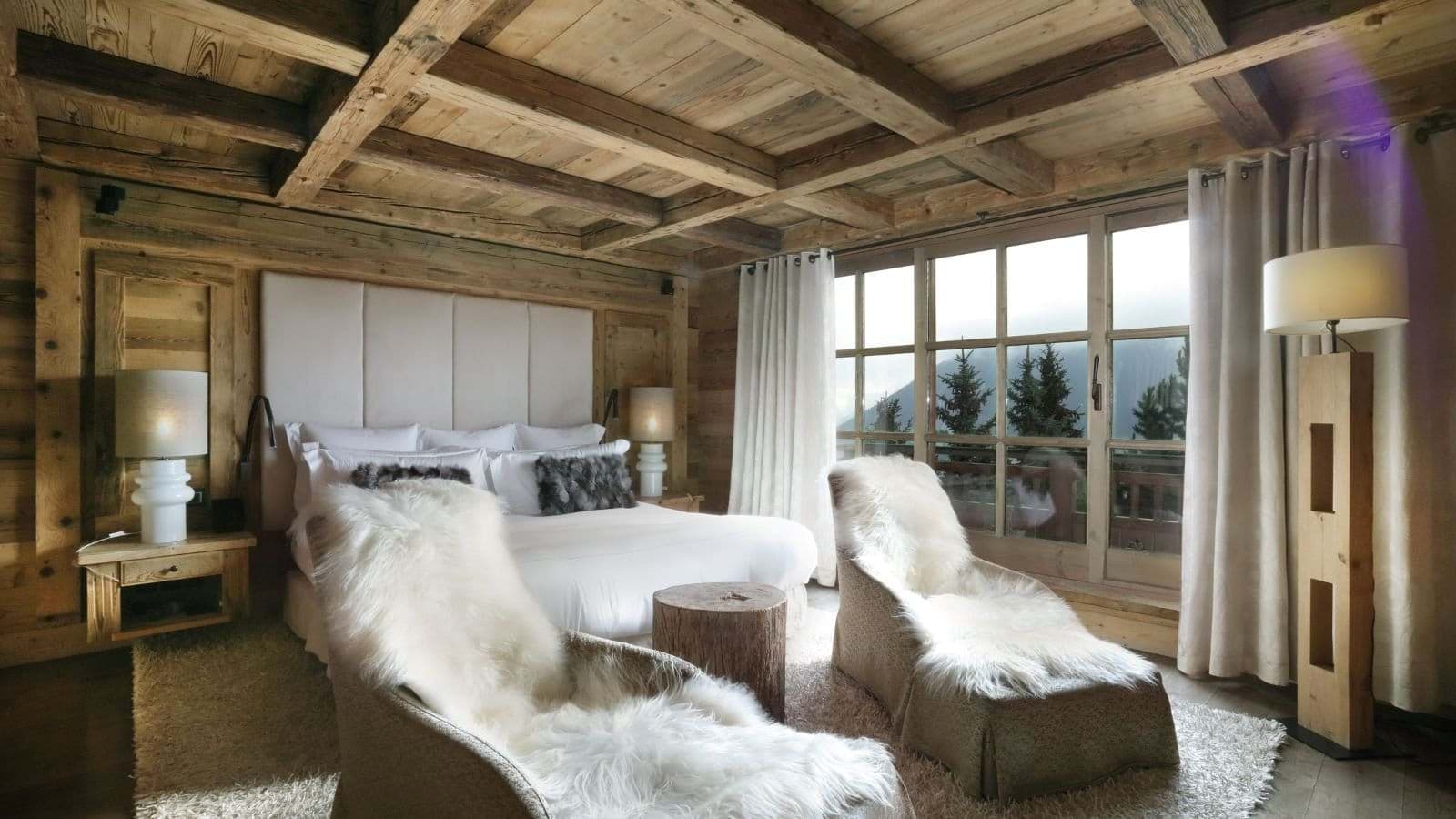 Primary bedroom with king bed, timber beams, and mountain-view balcony