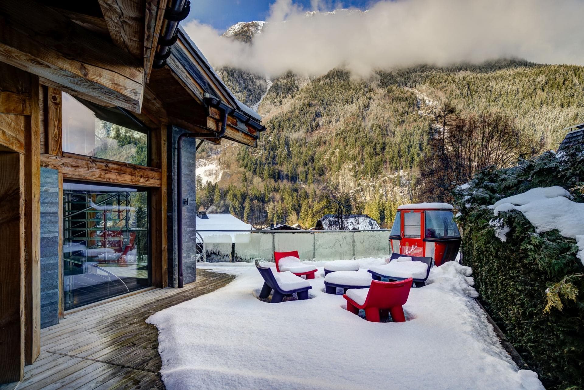 Snow-covered terrace featuring lounge seating and vintage gondola cabin with mountain views