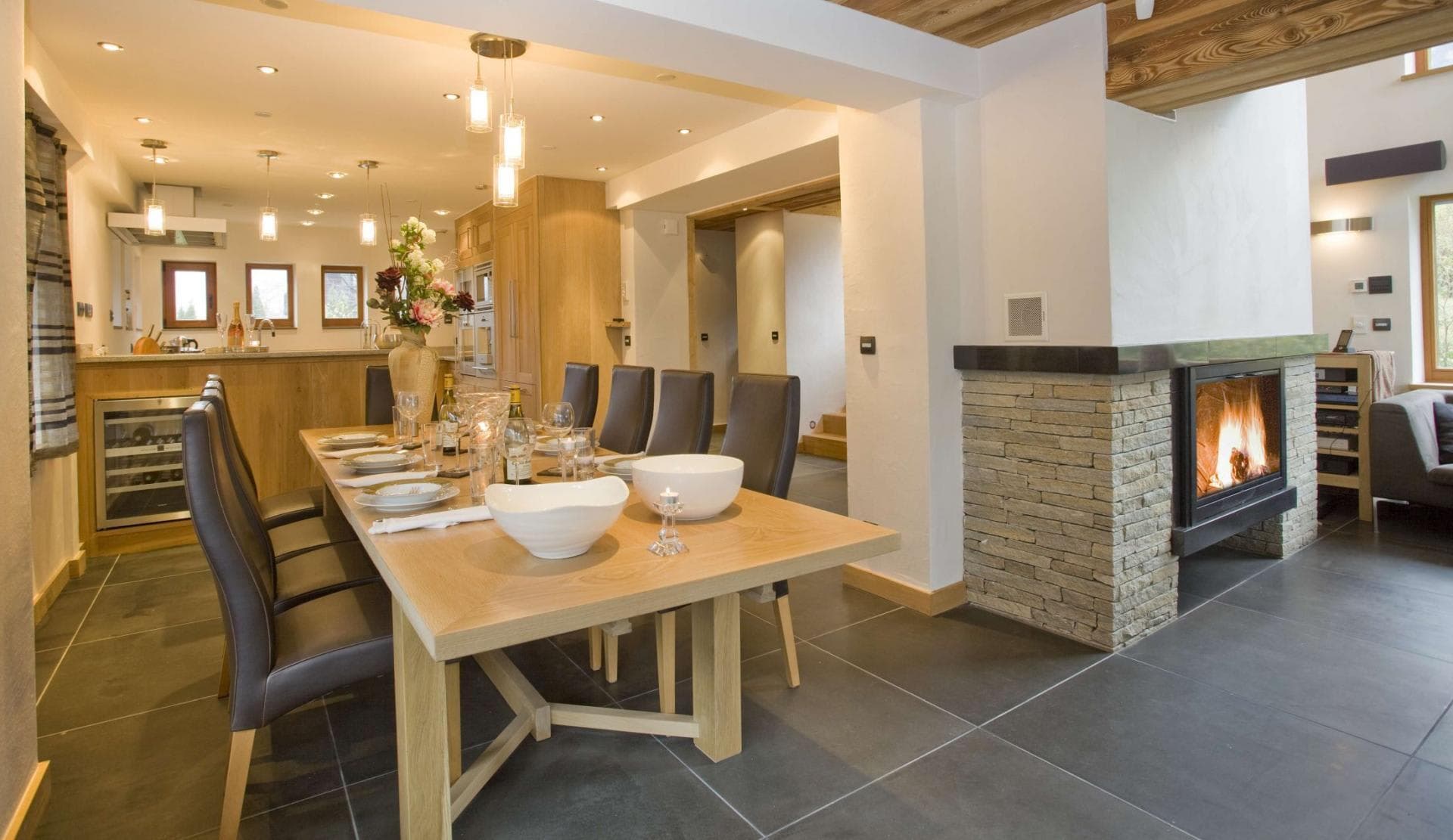 Dining area with seating for 10 beside stone fireplace and wine cooler