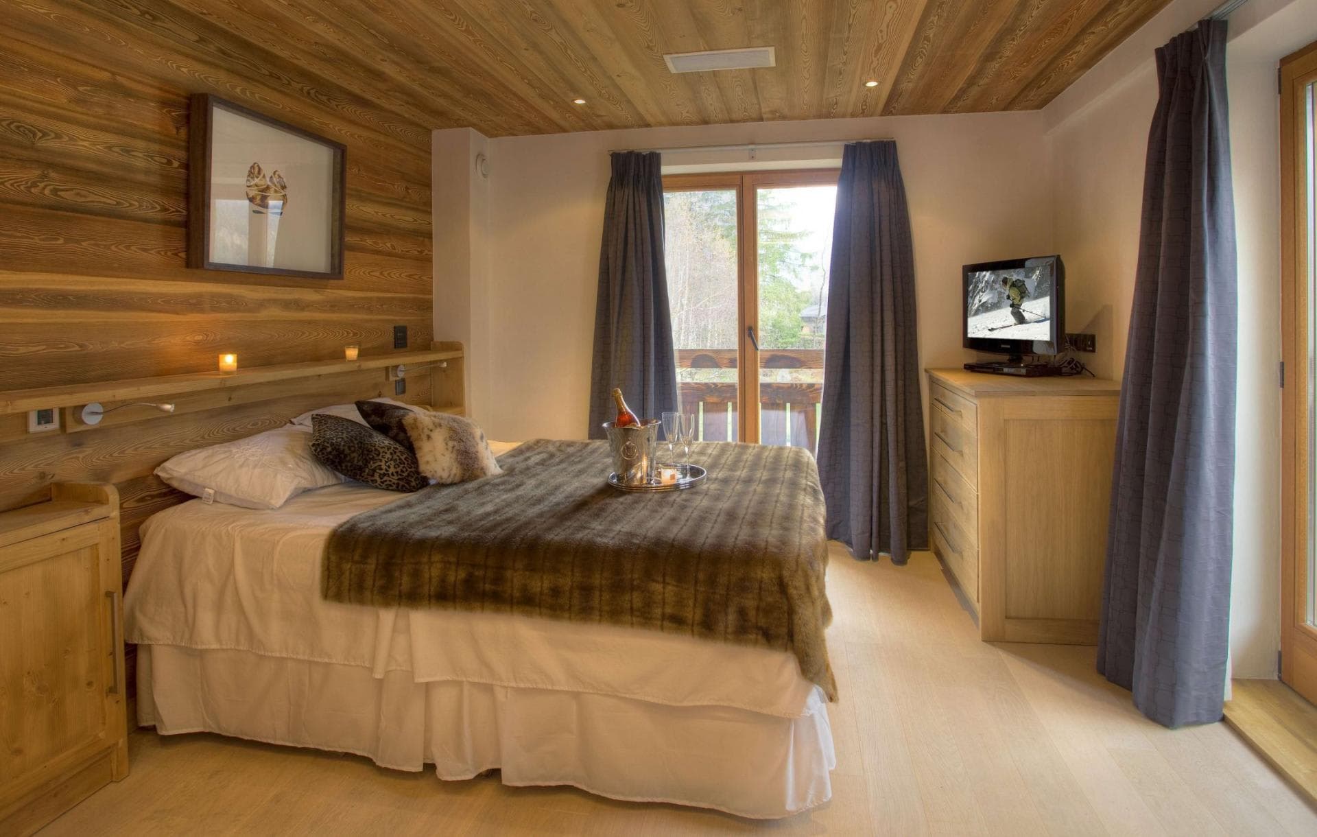 Guest bedroom with king bed, timber-clad walls, and private balcony access
