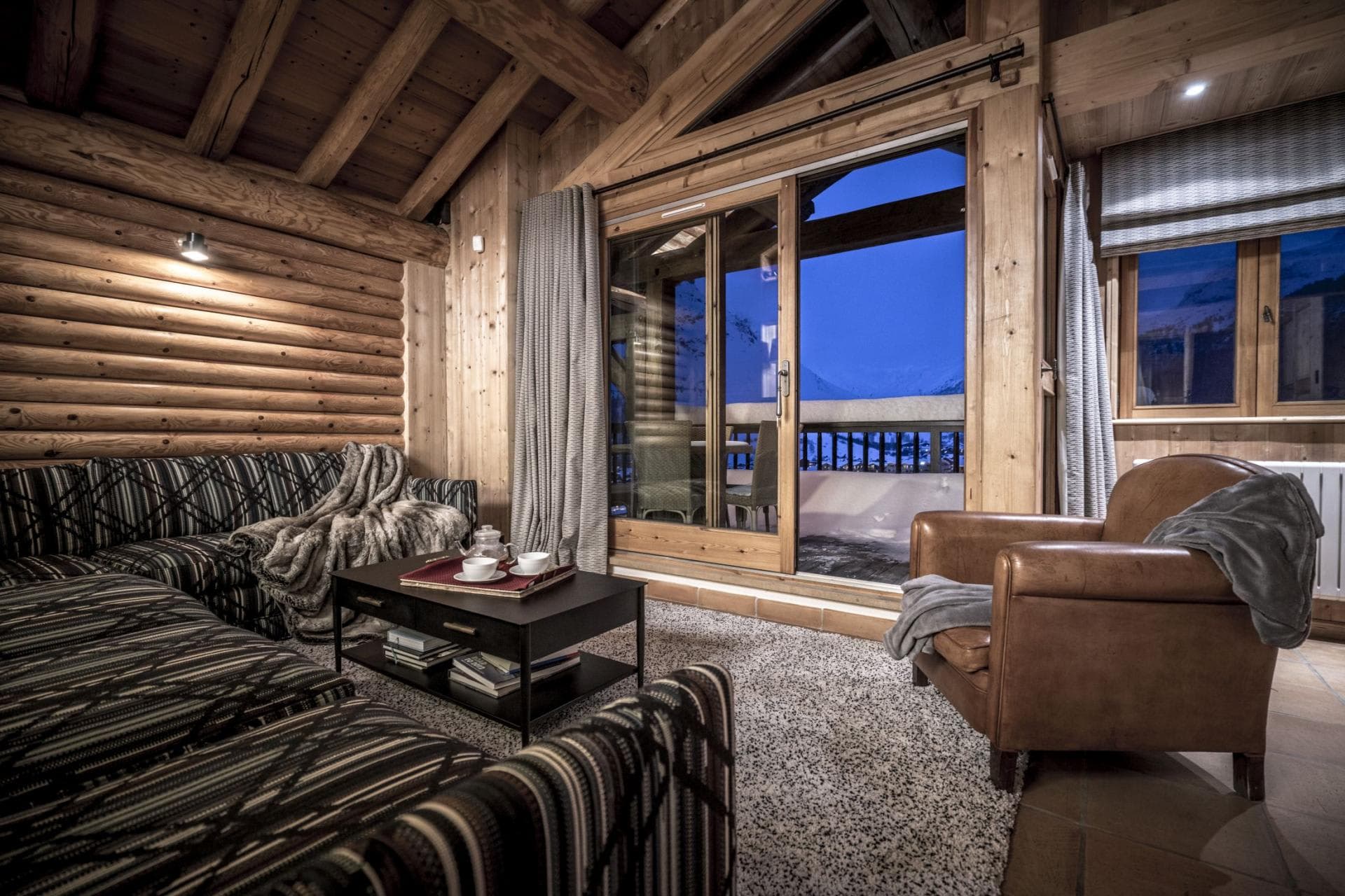 Log cabin living area with balcony access and mountain views