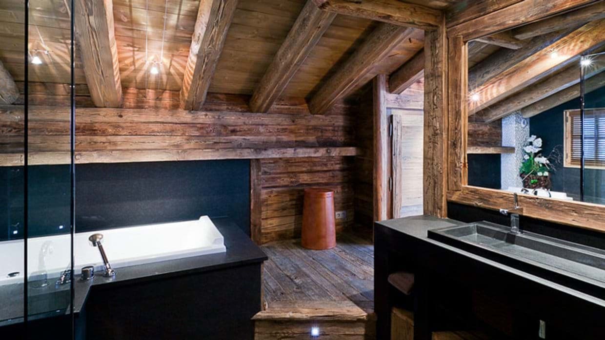 Bathroom with soaking tub, stone trough sink, and reclaimed wood beams
