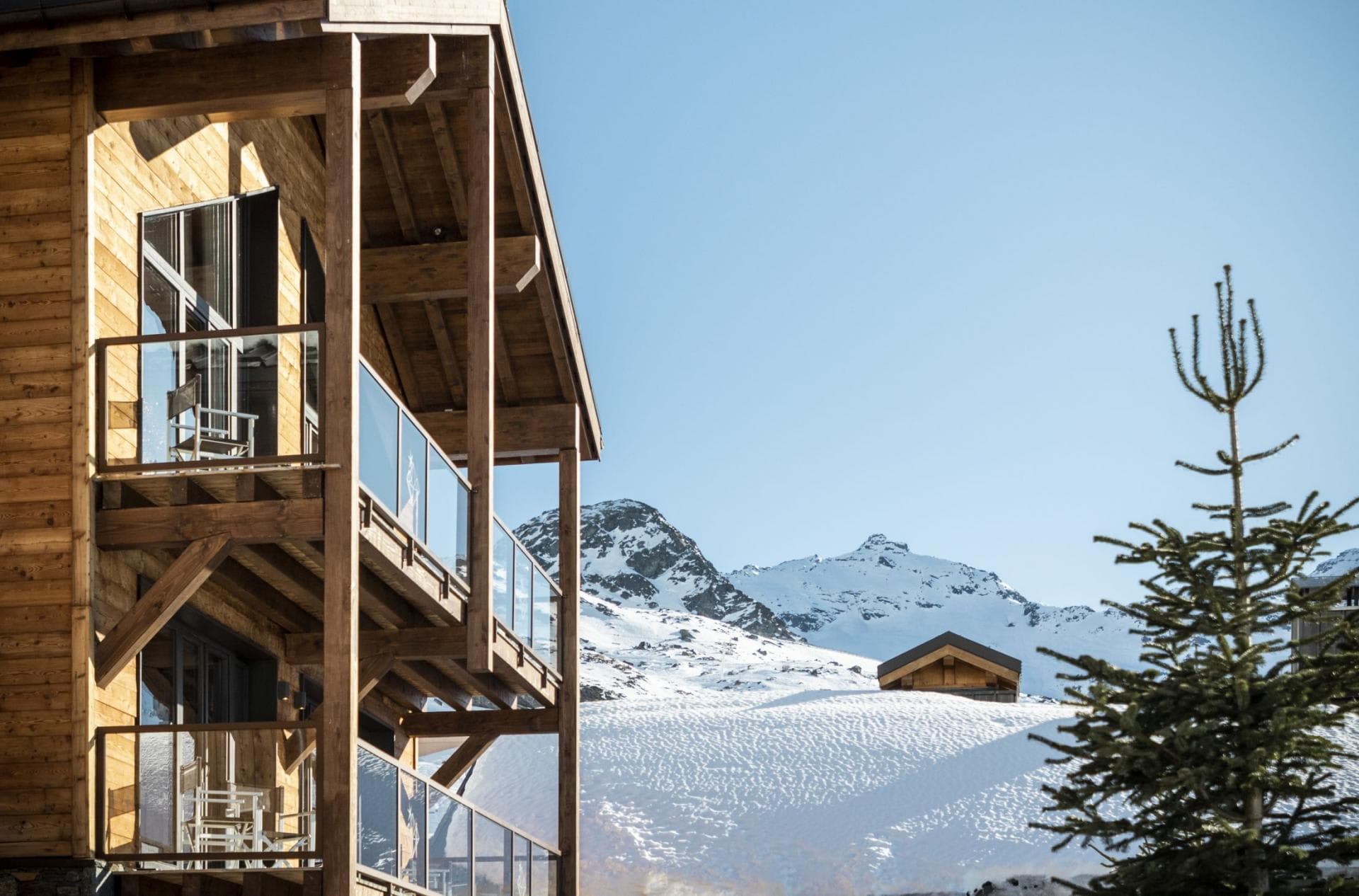 Wooden chalet balconies with glass railings and snow-capped mountain views