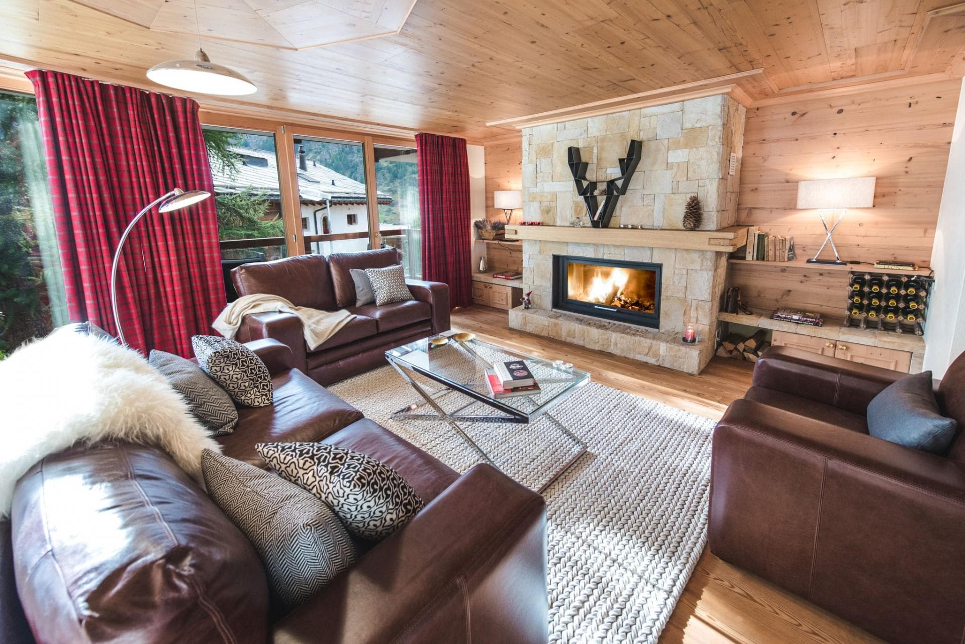 Living room with wood-burning stone fireplace and floor-to-ceiling mountain views