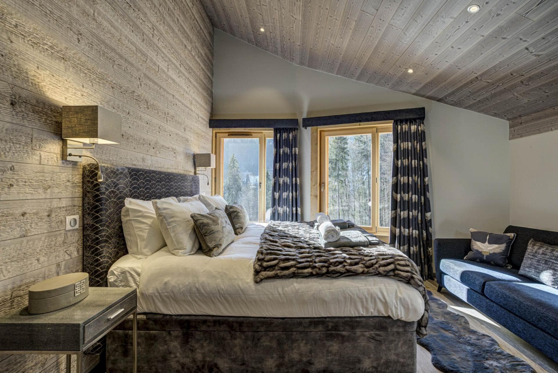 Bedroom with king bed, vaulted wood ceiling, and forest-facing windows
