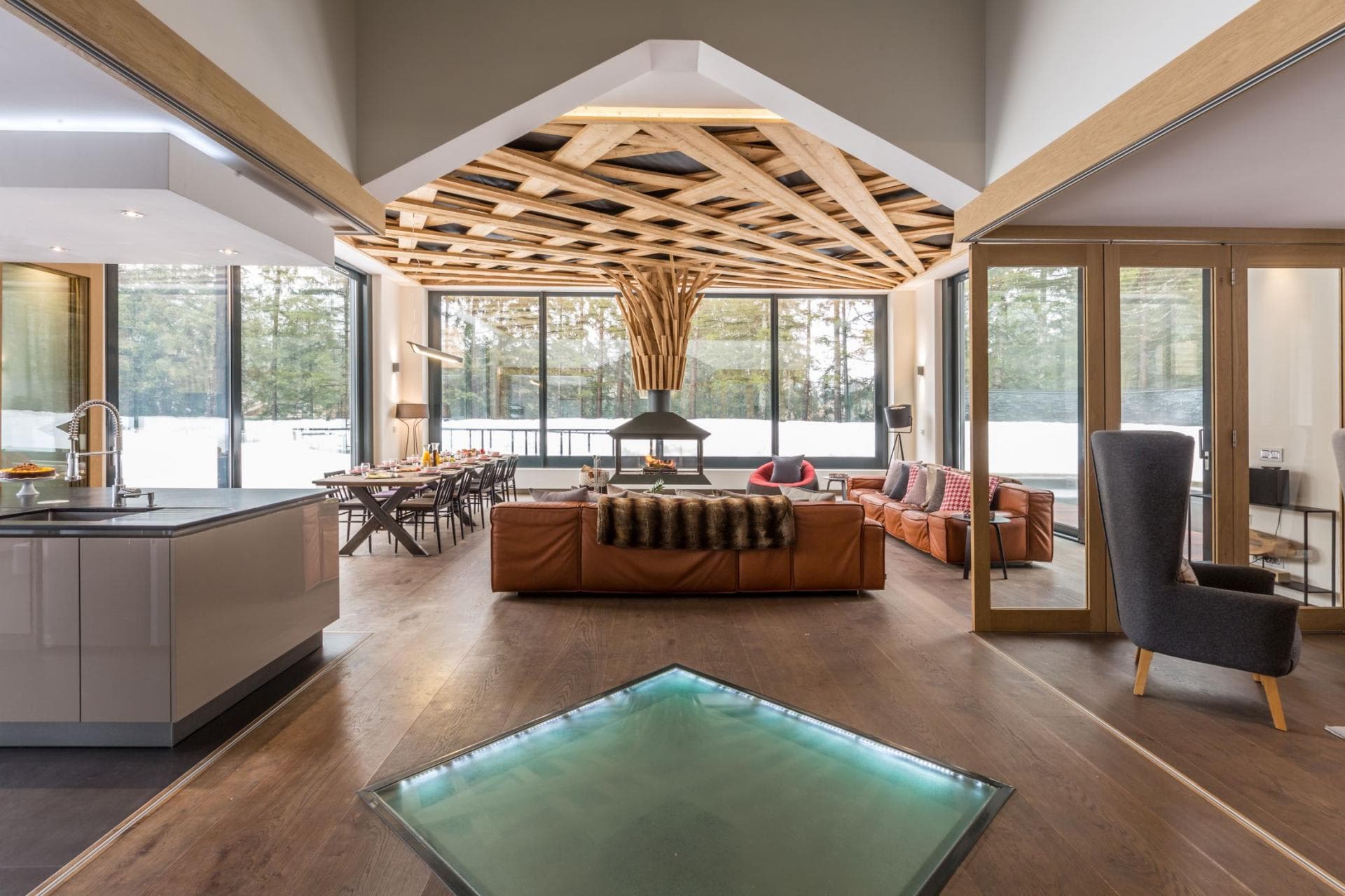 Open-plan living area with 360-degree fireplace and glass floor panel