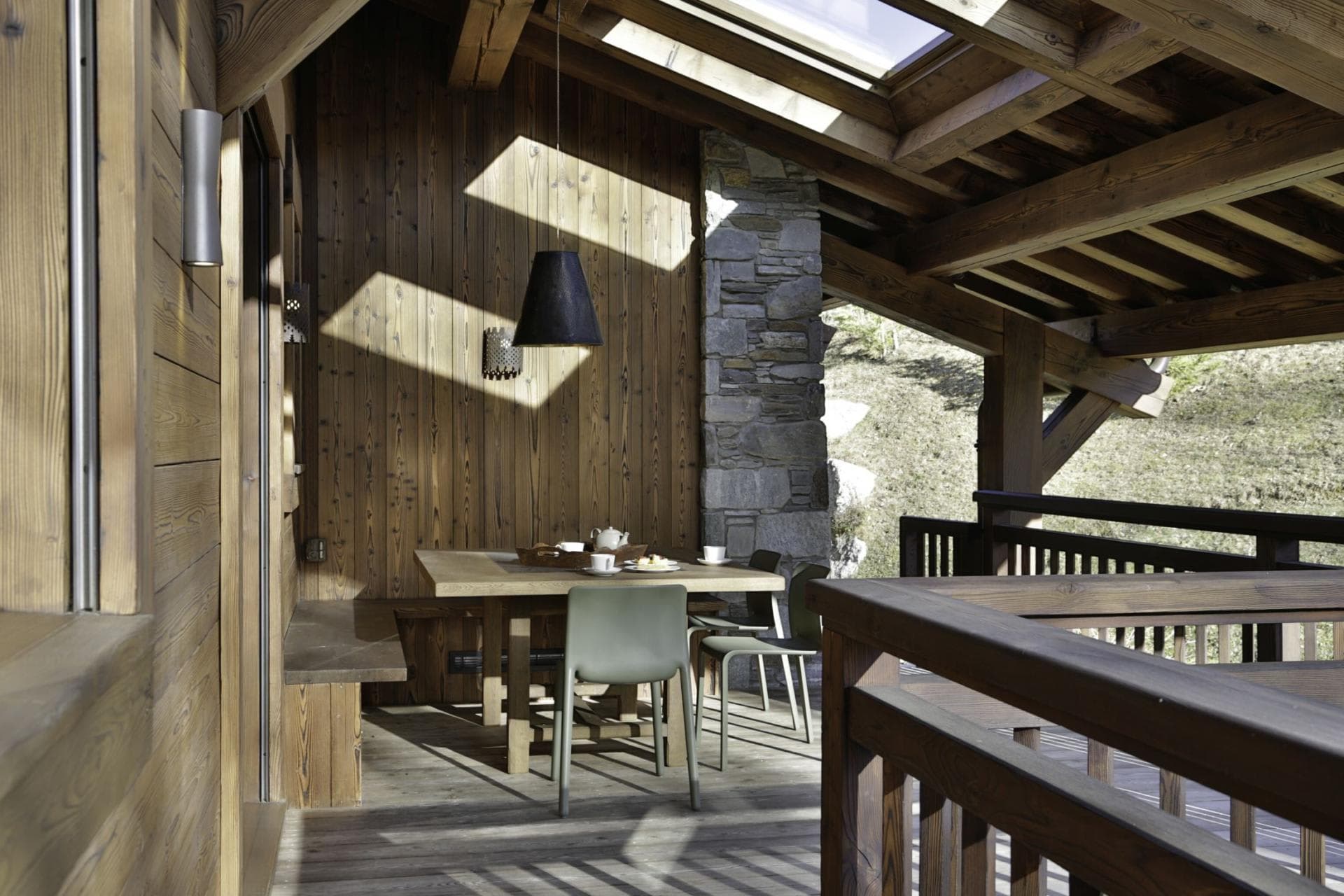 Covered balcony dining area with wood-bench seating and skylight
