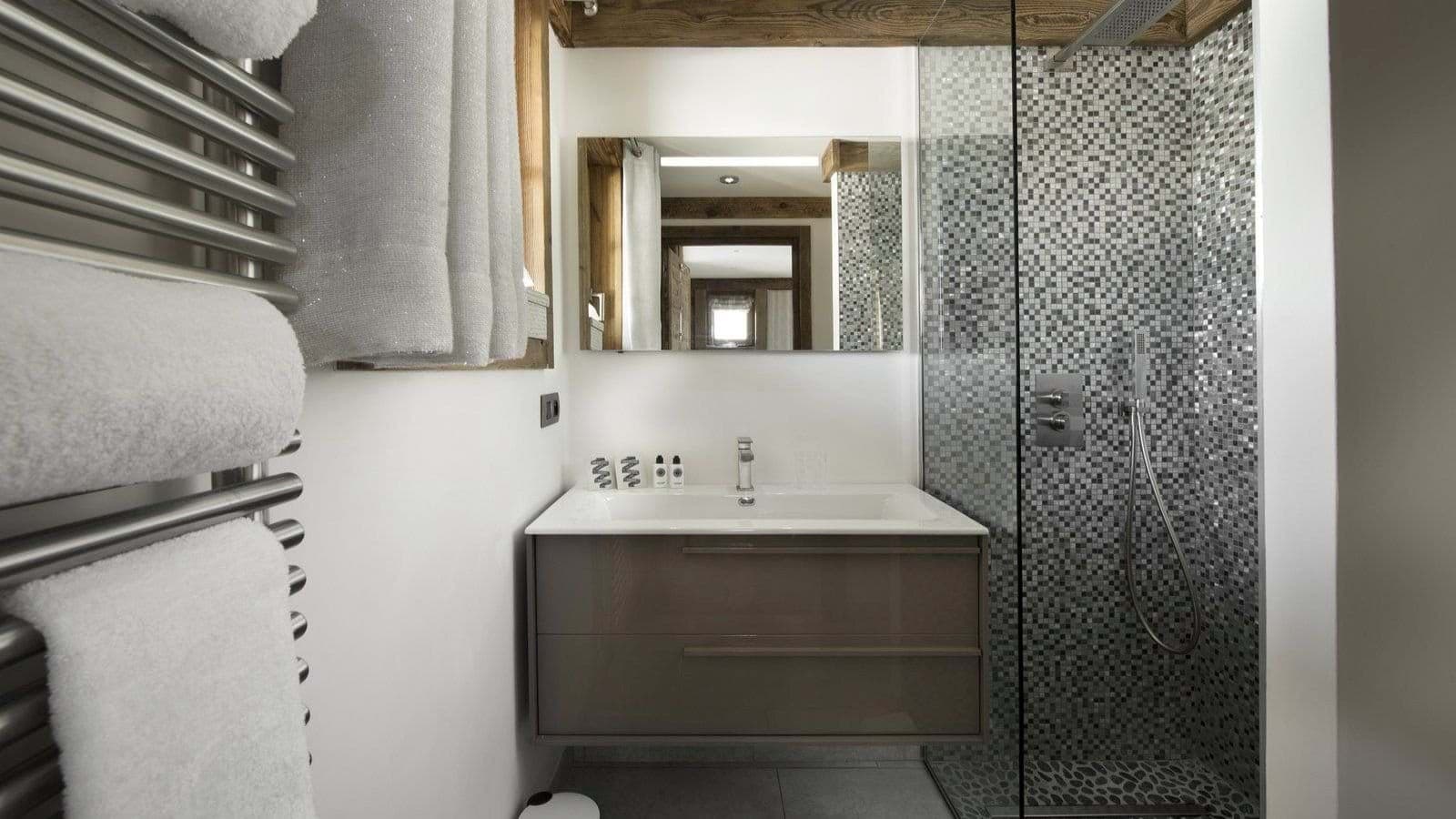 Bathroom featuring heated towel rack and walk-in shower with rainfall head