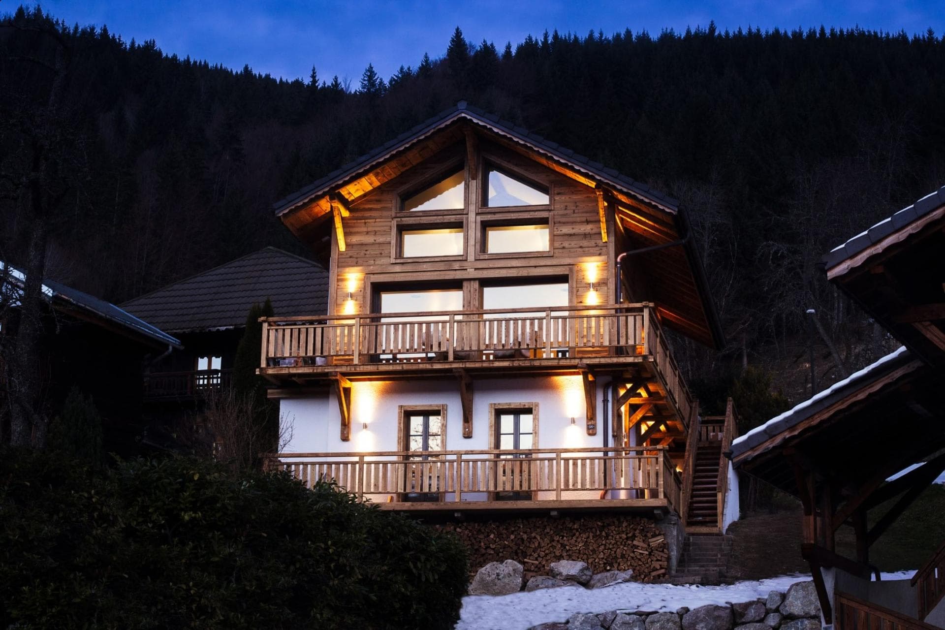 Chalet exterior with two levels of wrap-around balconies and forest backdrop