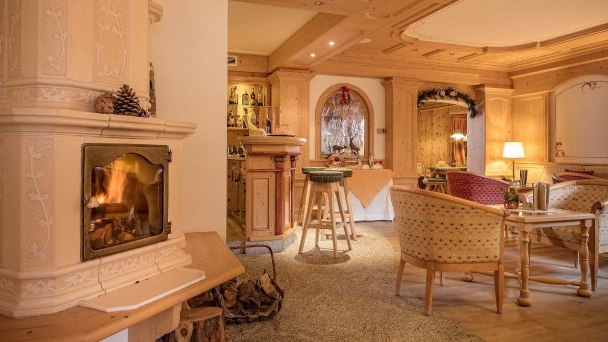Lounge with wood-burning stove, wet bar, and traditional Tyrolean pine paneling