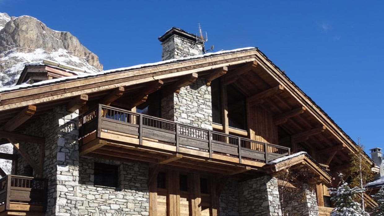Stone and timber chalet exterior with private balcony and mountain views