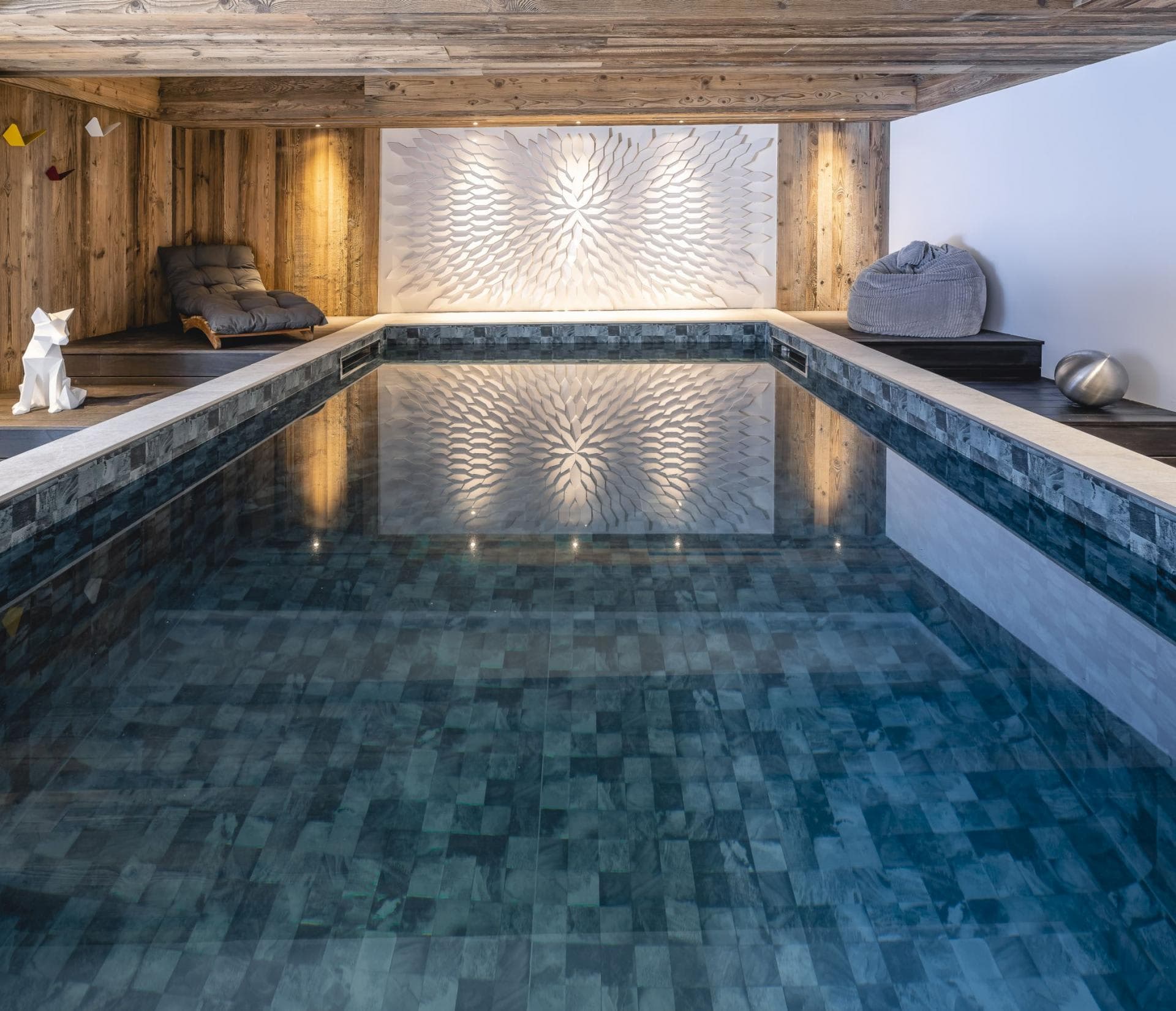 Indoor heated pool with wood-paneled walls and lounge seating