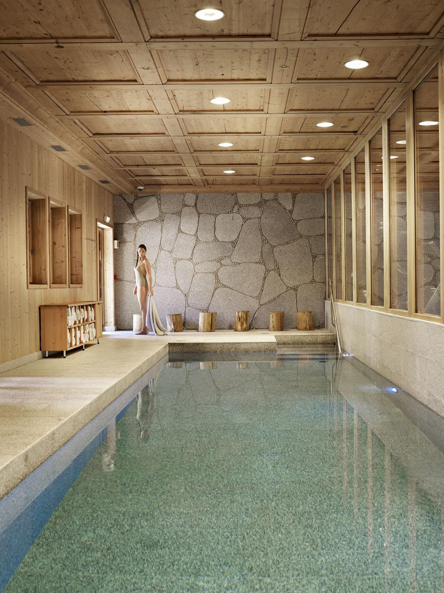 Indoor pool with stone mosaic wall and wood-paneled ceiling