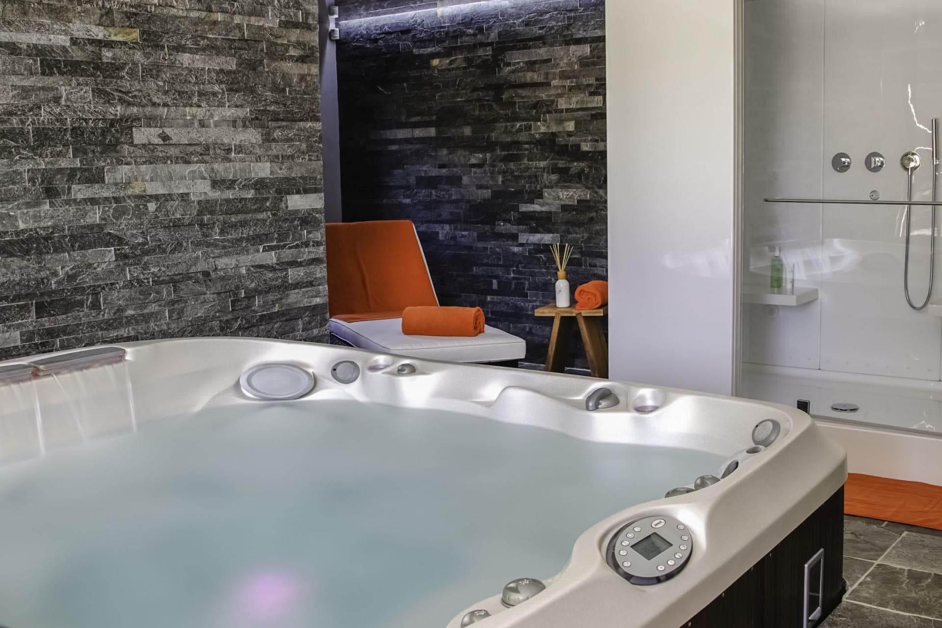 Indoor hot tub area with adjacent steam shower and lounge seating