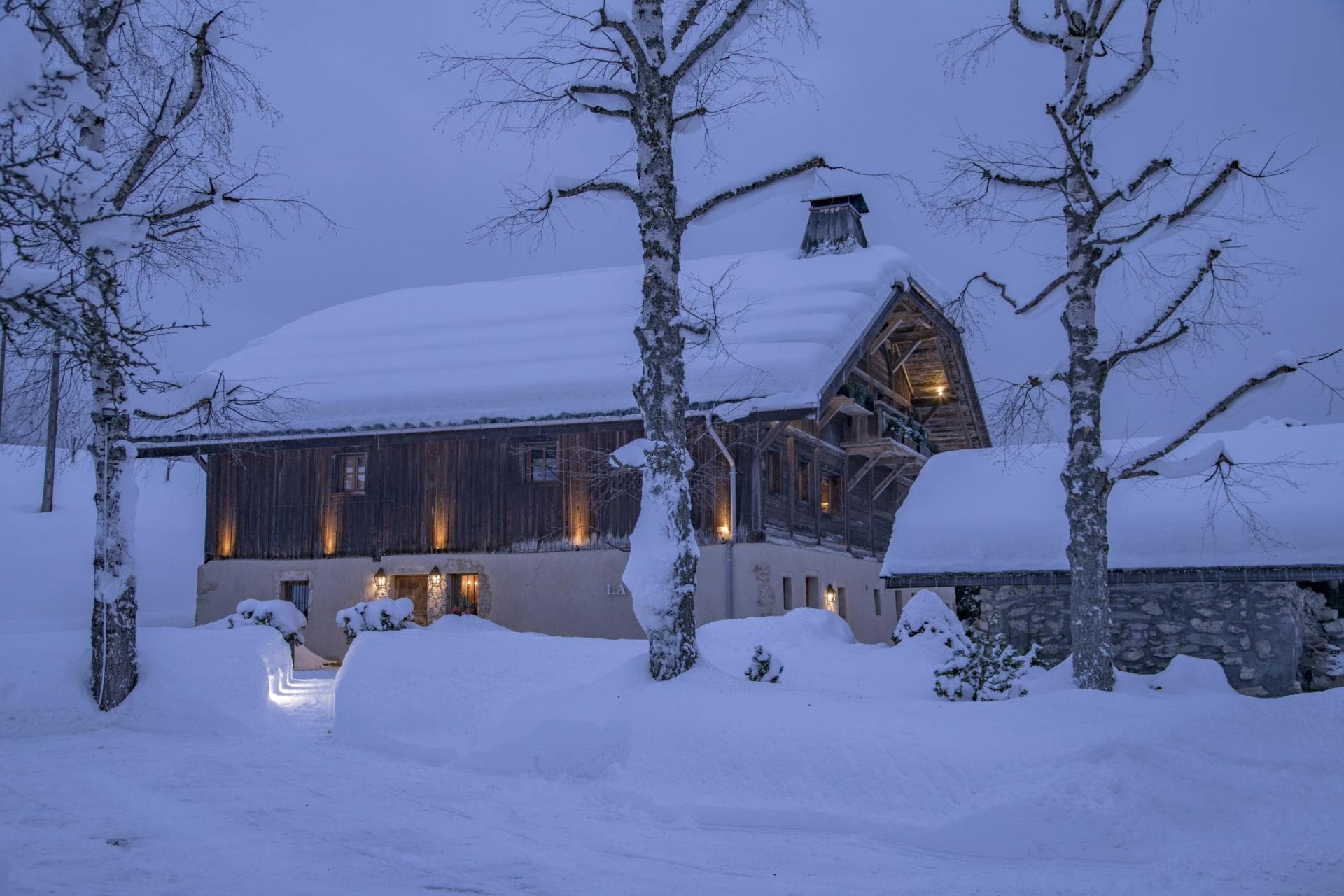 Ski-in chalet with traditional timber facade and snow-cleared stone entrance