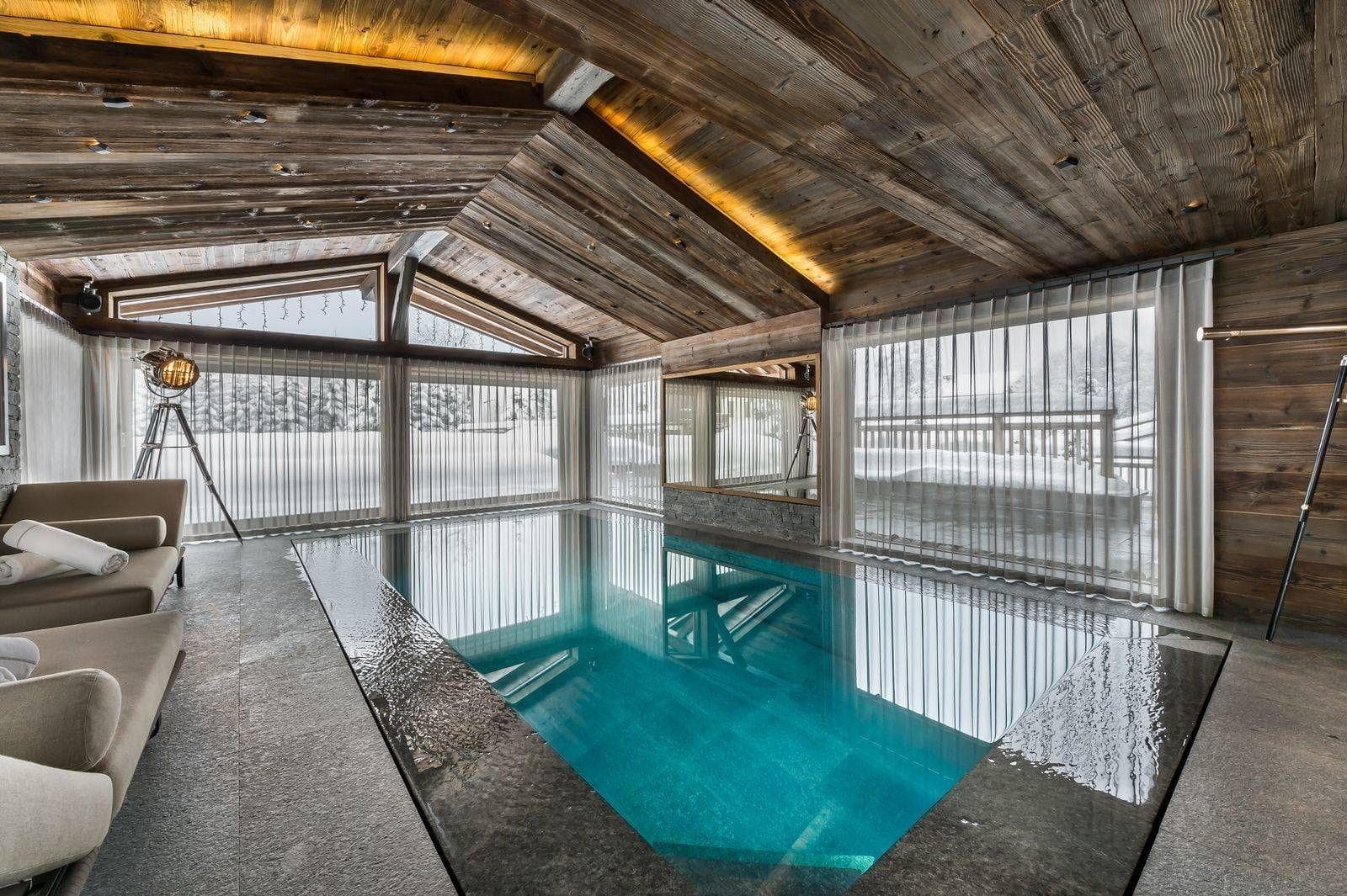 Indoor pool with vaulted timber ceiling and views of snowy terrace