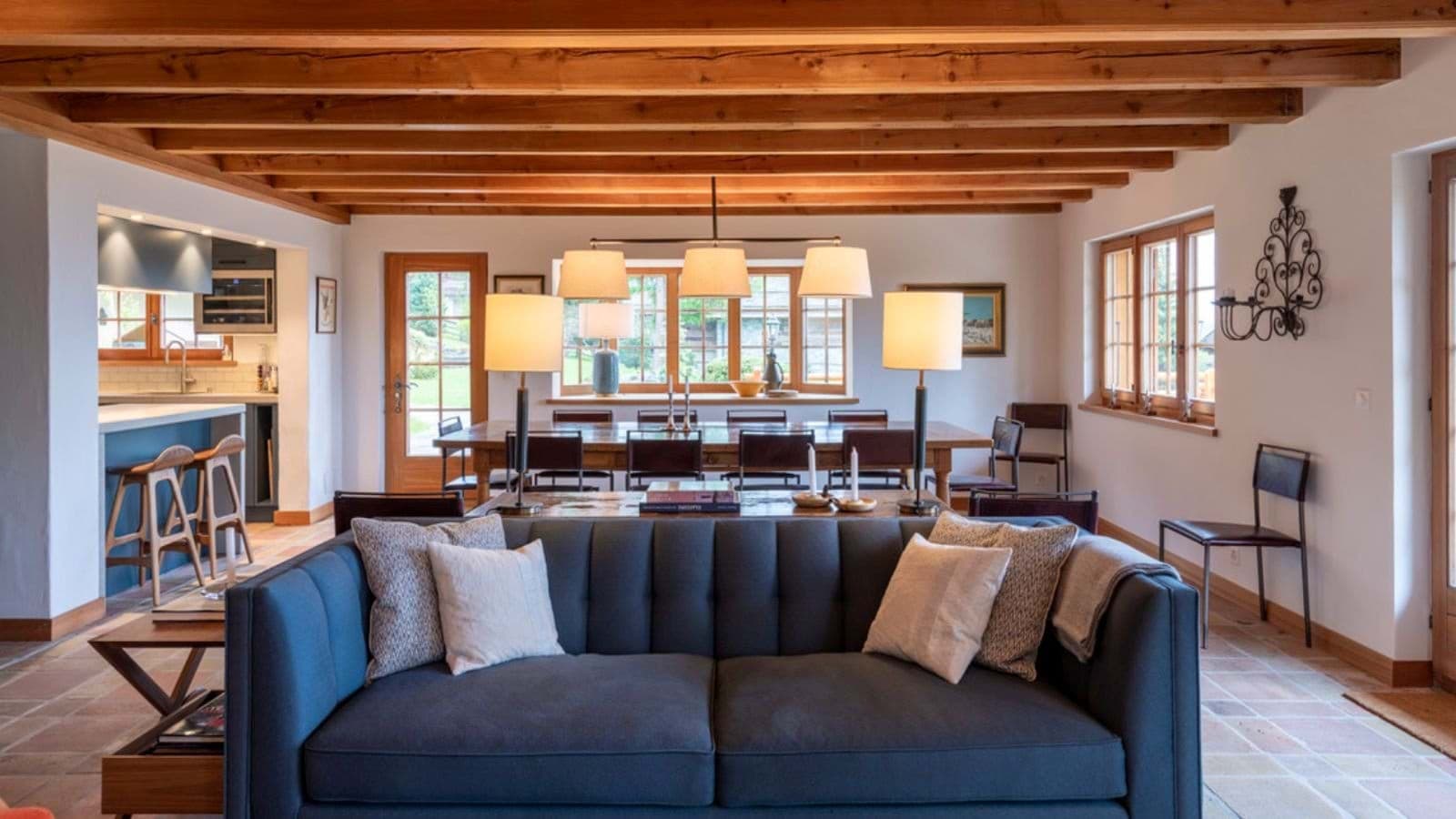 Open-plan living area with exposed wood beams and dining for 8