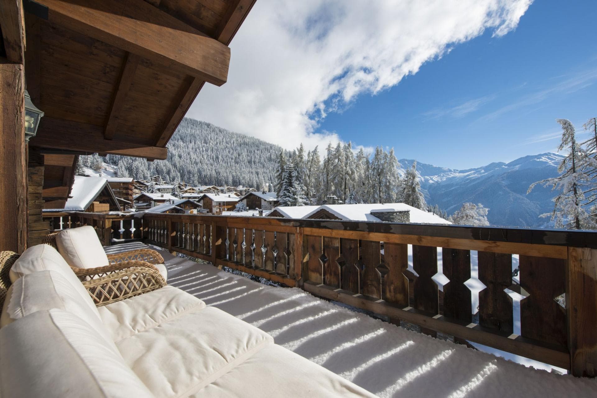 Covered wooden balcony with lounge seating and panoramic alpine valley views