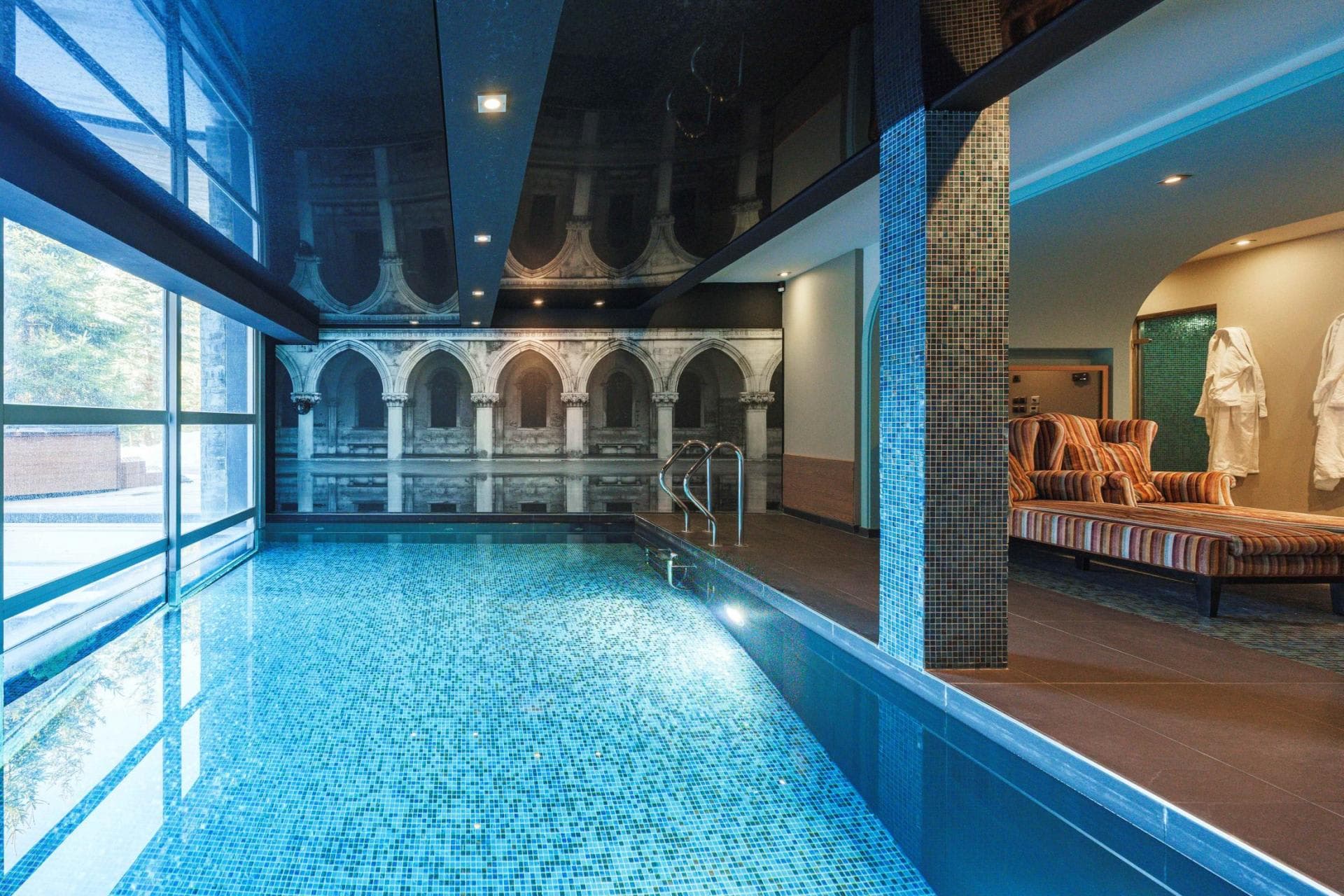 Indoor pool with architectural mural and adjacent lounge area