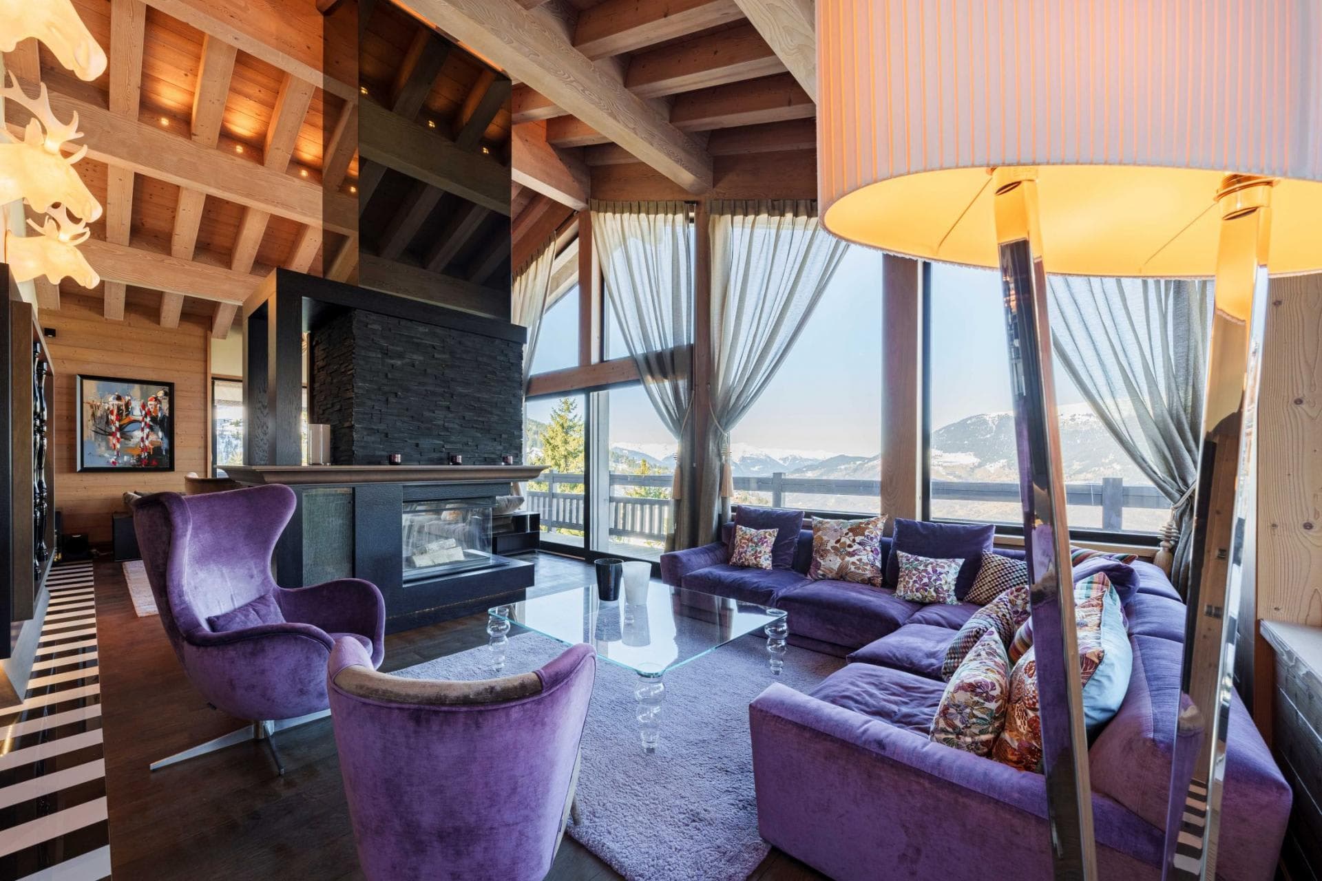 Living area with wood-burning fireplace and floor-to-ceiling mountain views