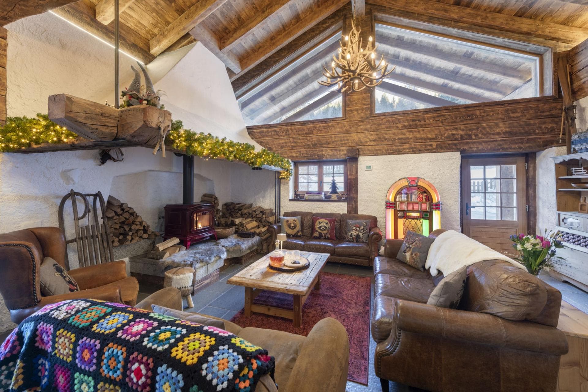 Living area with wood-burning stove, vaulted ceilings, and vintage jukebox