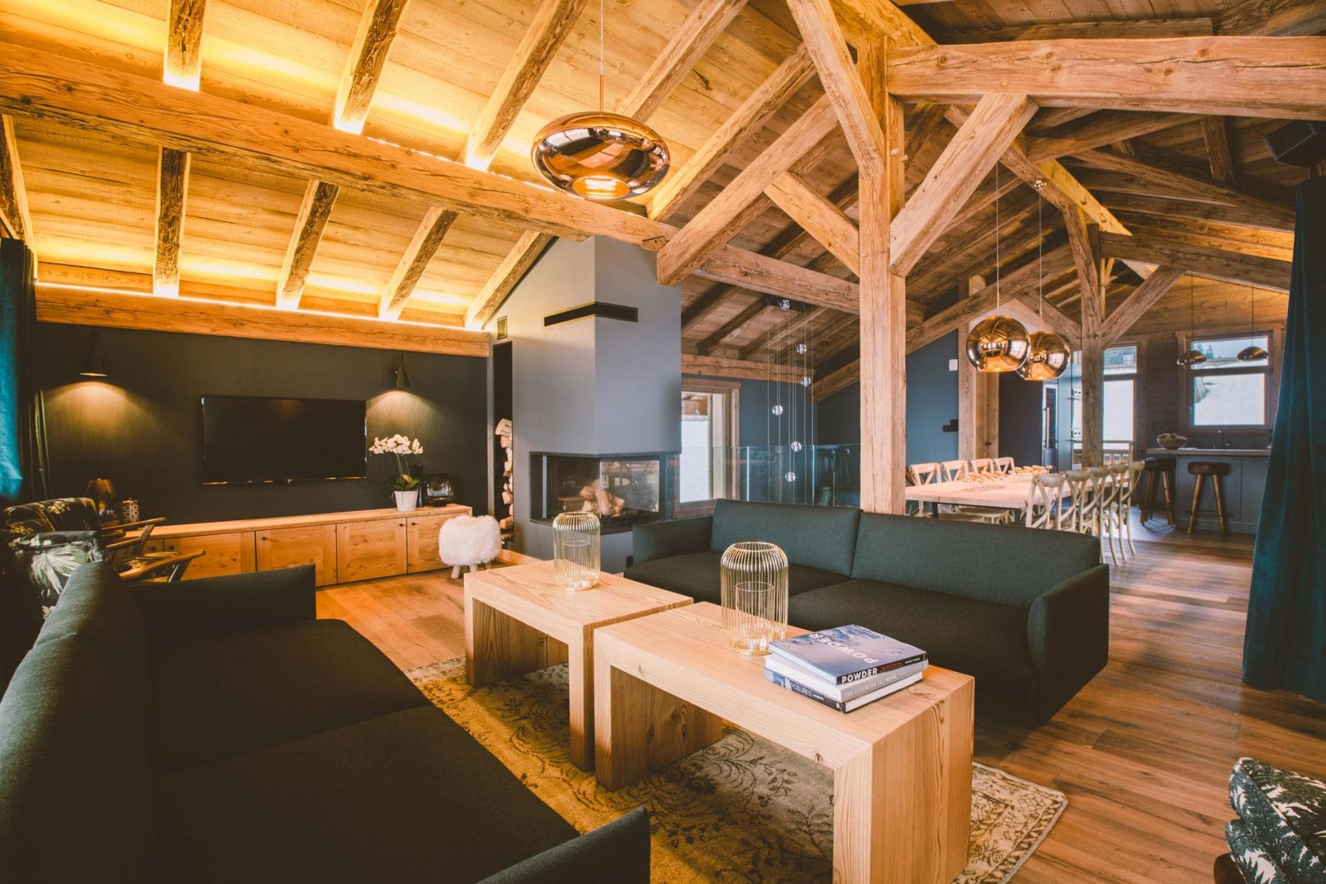 Open-plan living area with three-sided fireplace and vaulted timber ceilings