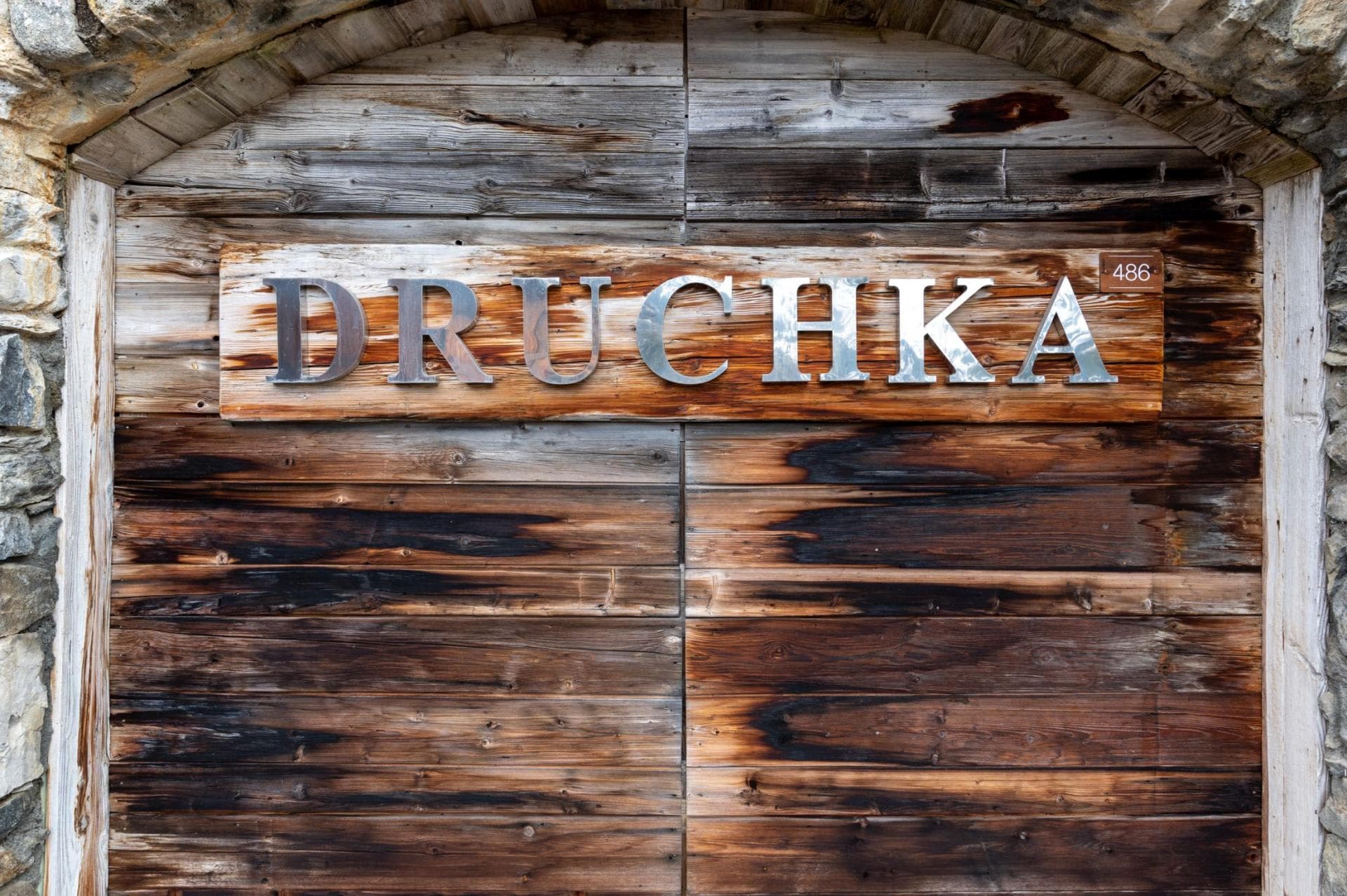 Chalet entrance sign featuring property name in metal lettering on reclaimed wood