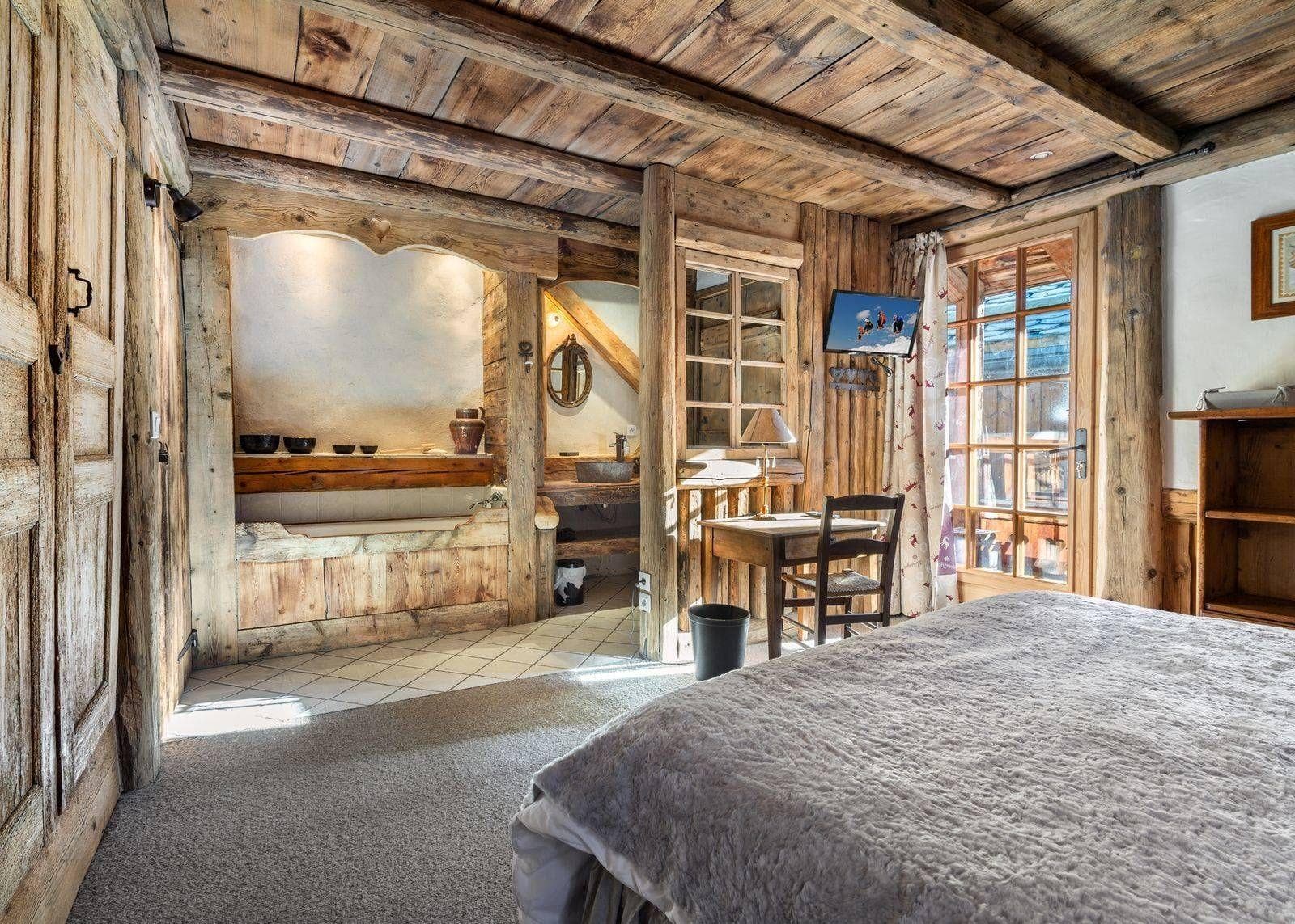 Bedroom with workstation and ensuite bathroom featuring reclaimed wood beams