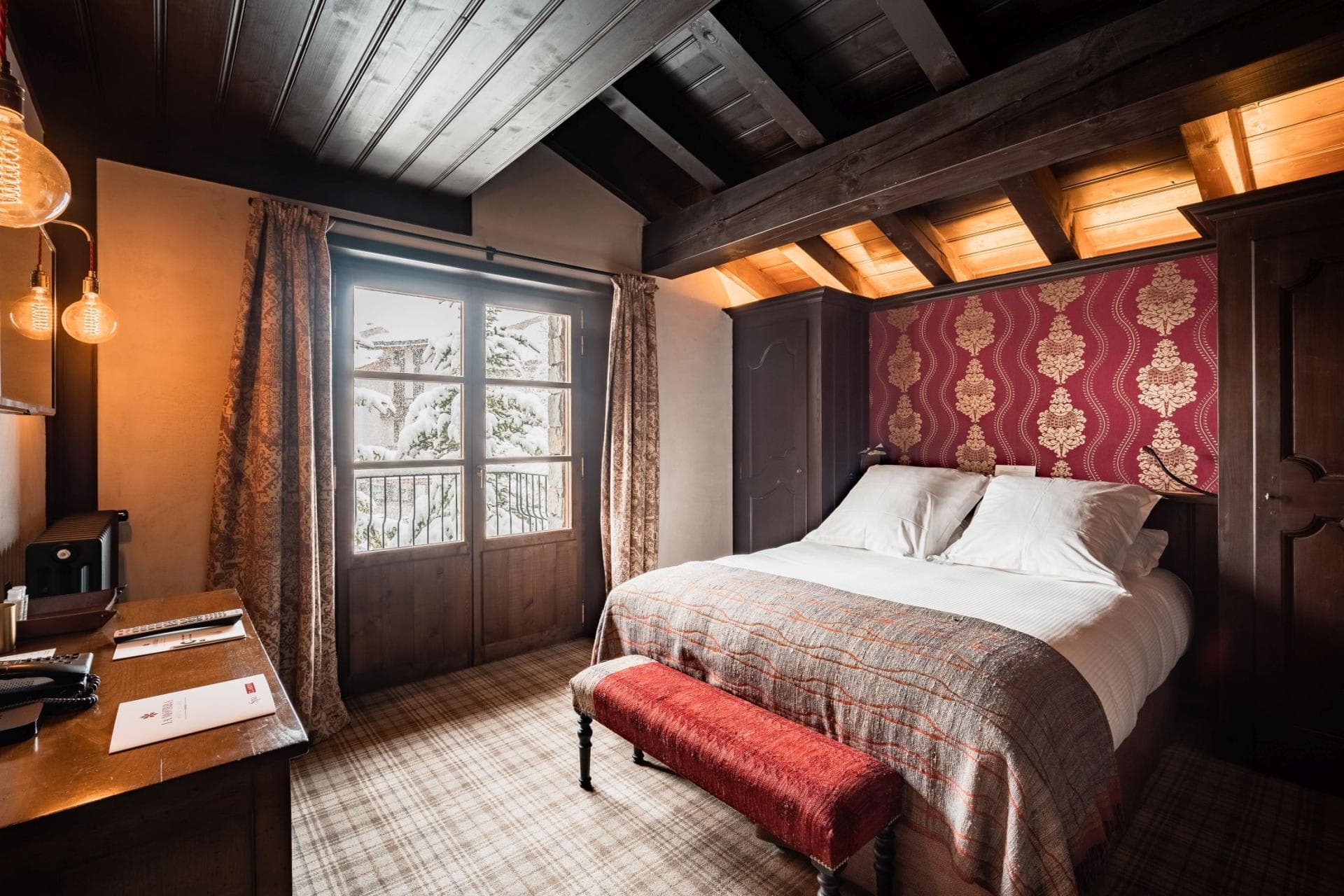 Bedroom with queen bed, Juliet balcony, and exposed wood ceiling