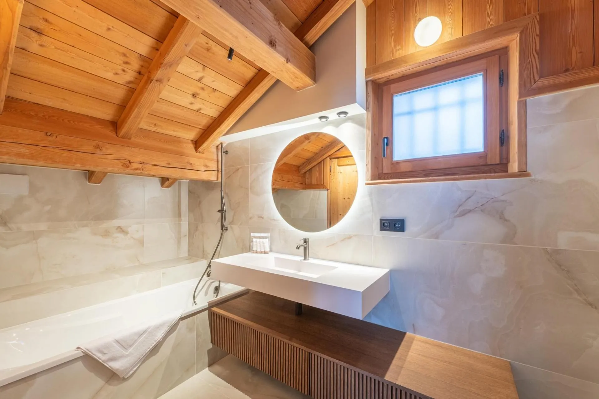 Bathroom with bathtub, illuminated mirror and timber ceiling