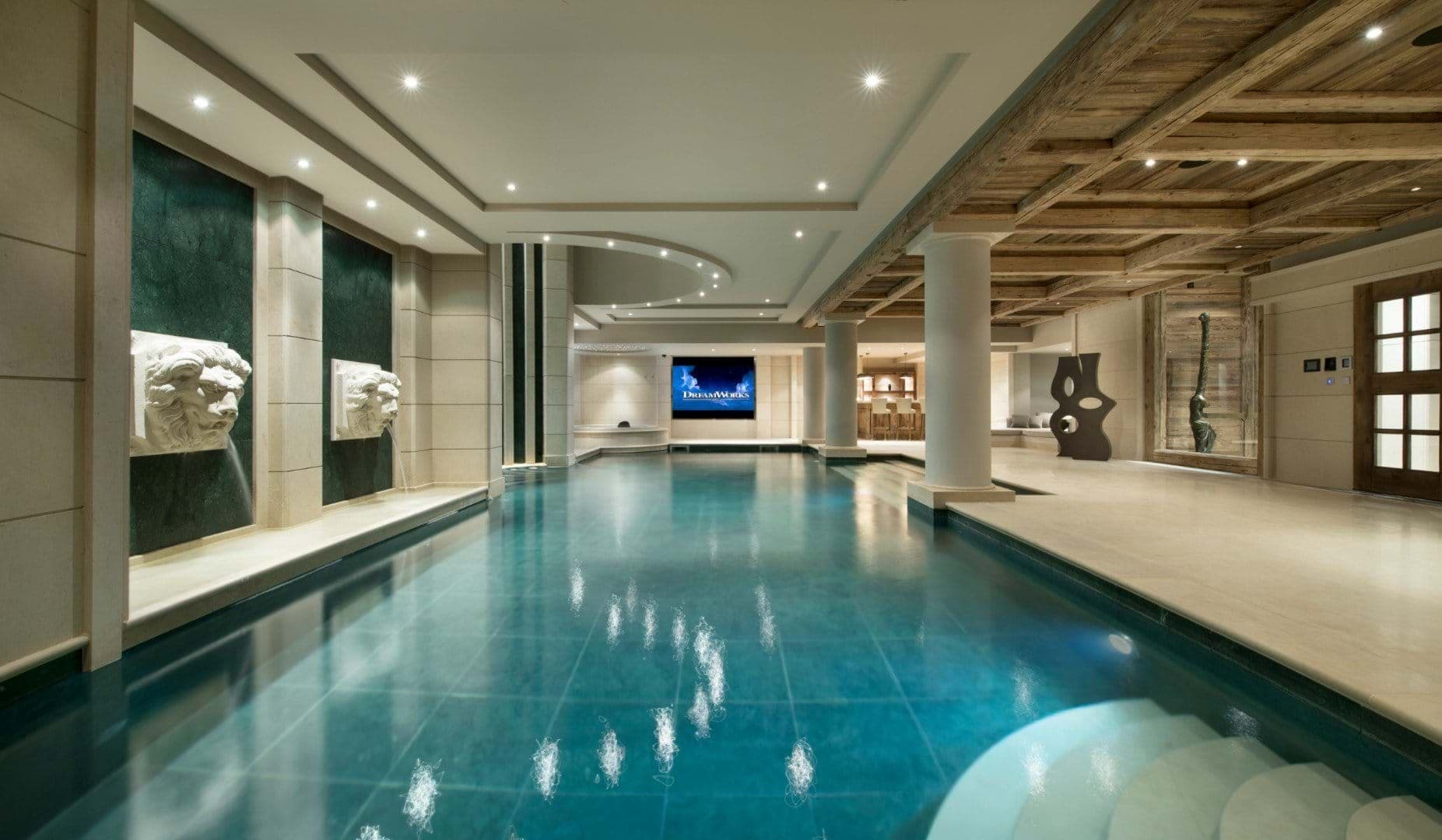 Indoor pool with projector screen and lion head water features