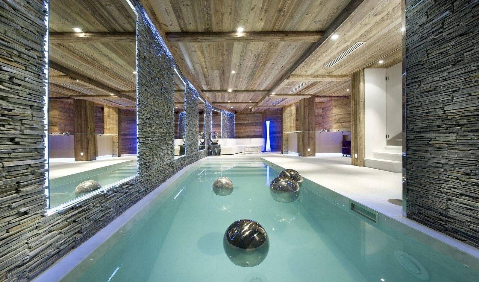 Indoor lap pool with stone accent walls and timber ceilings